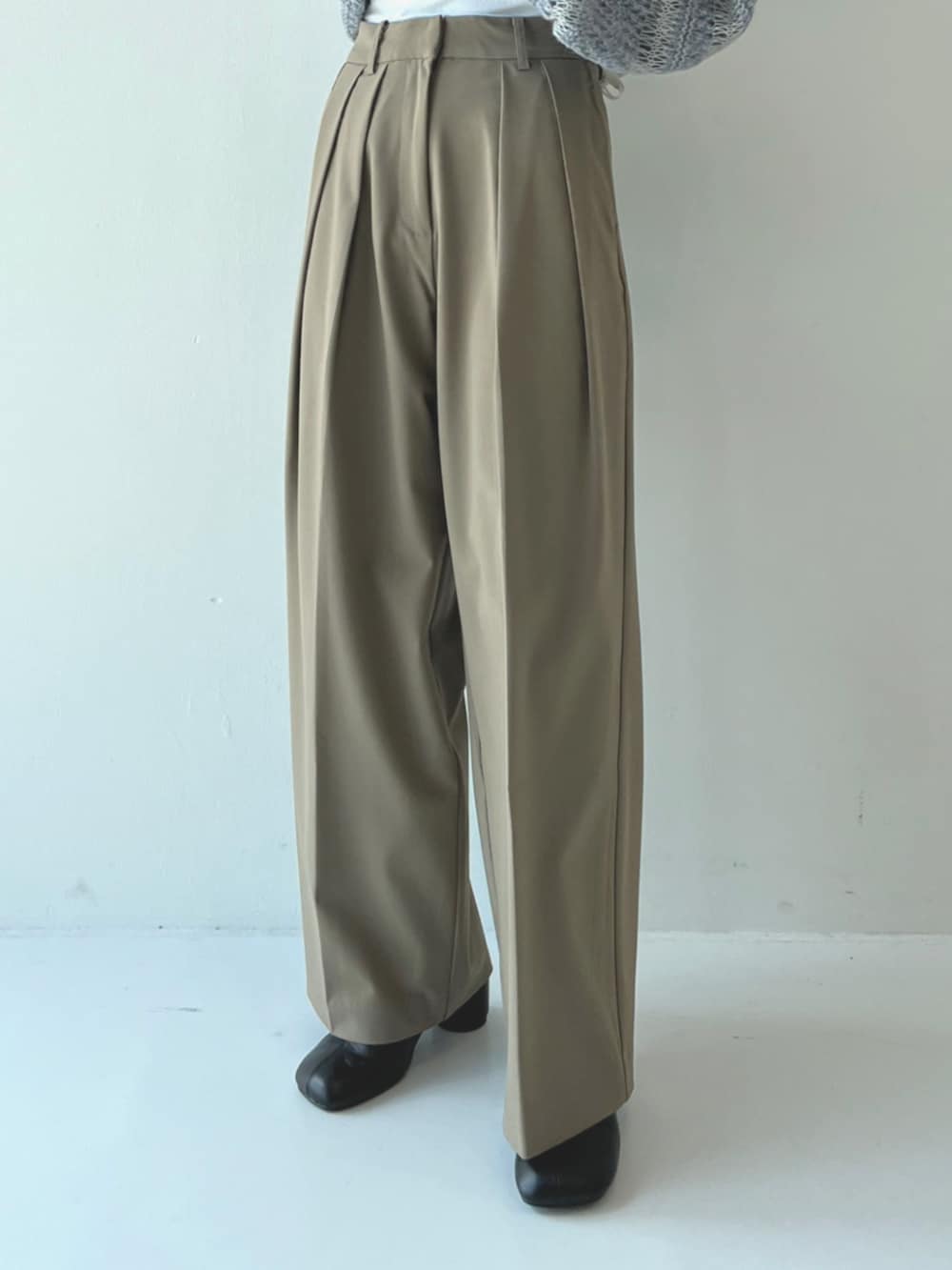 ブルー系のニット/セーター、ブラック系のハンドバッグ、グリーン系のスラックスを着用したレディースの秋コーディネートの2枚目の写真