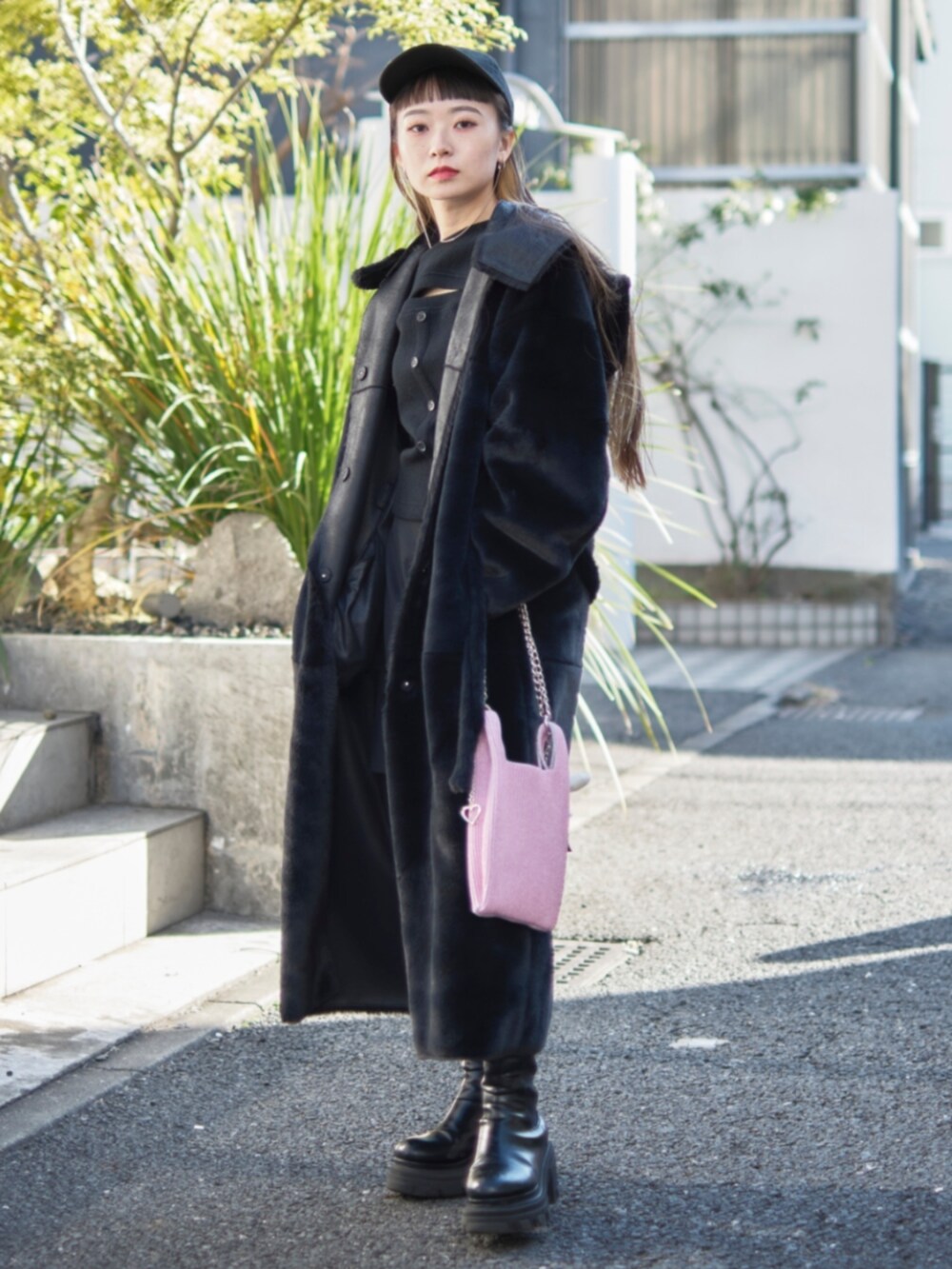 ピンク系のショルダーバッグ、ブラック系のピーコート、ブラック系のキャップを着用したレディースの冬コーディネートの2枚目の写真