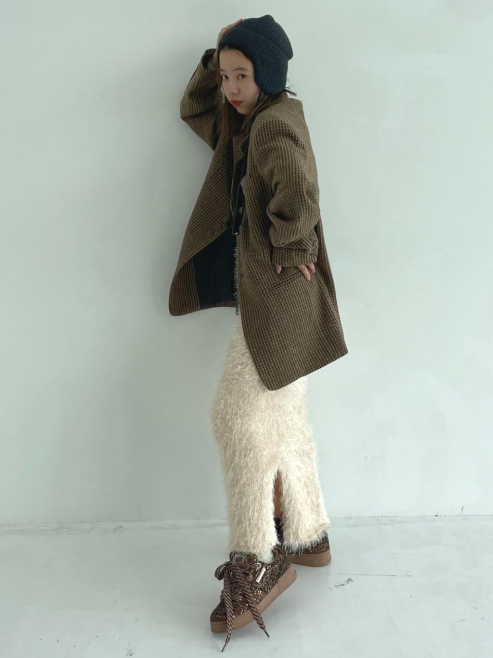 イエロー系のテーラードジャケット、ホワイト系のスカート、ブラウン系のスニーカーを着用したレディースの秋コーディネートの2枚目の写真