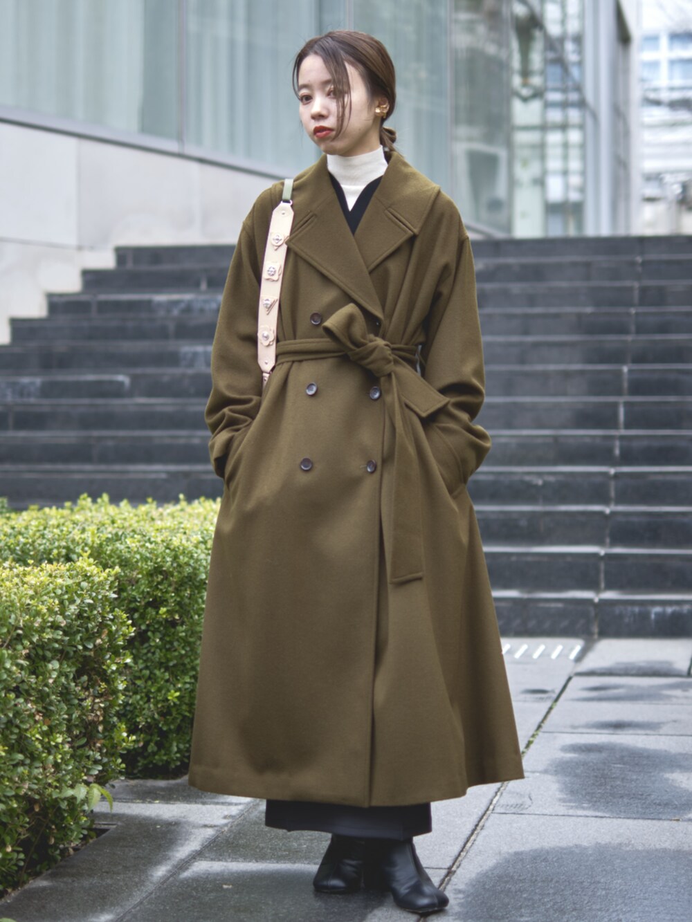 グリーン系のチェスターコートを着用したレディースの冬コーディネートの2枚目の写真
