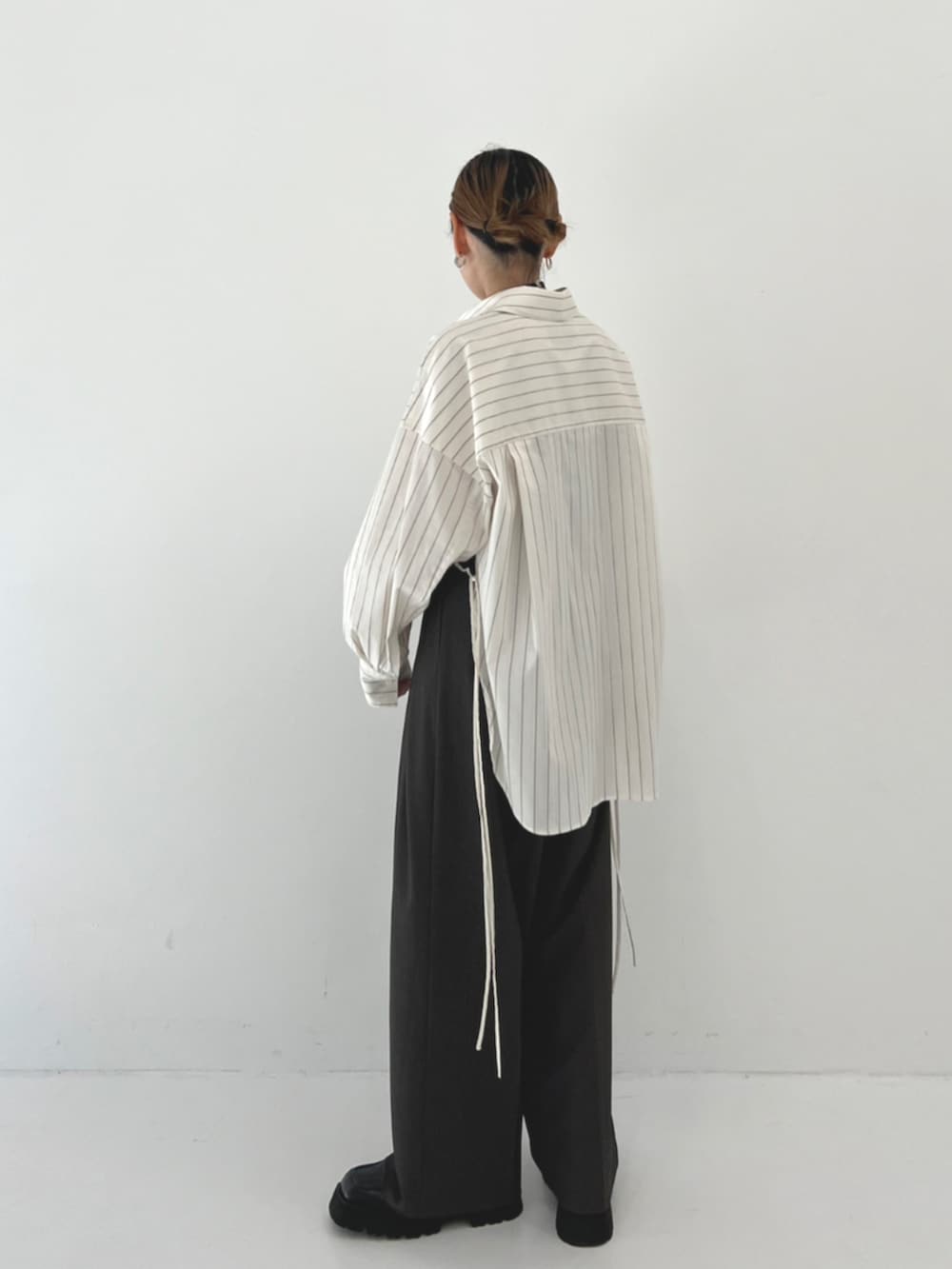 グレー系のスラックス、ブラック系のバングル/リストバンドを着用したレディースの秋コーディネートの3枚目の写真