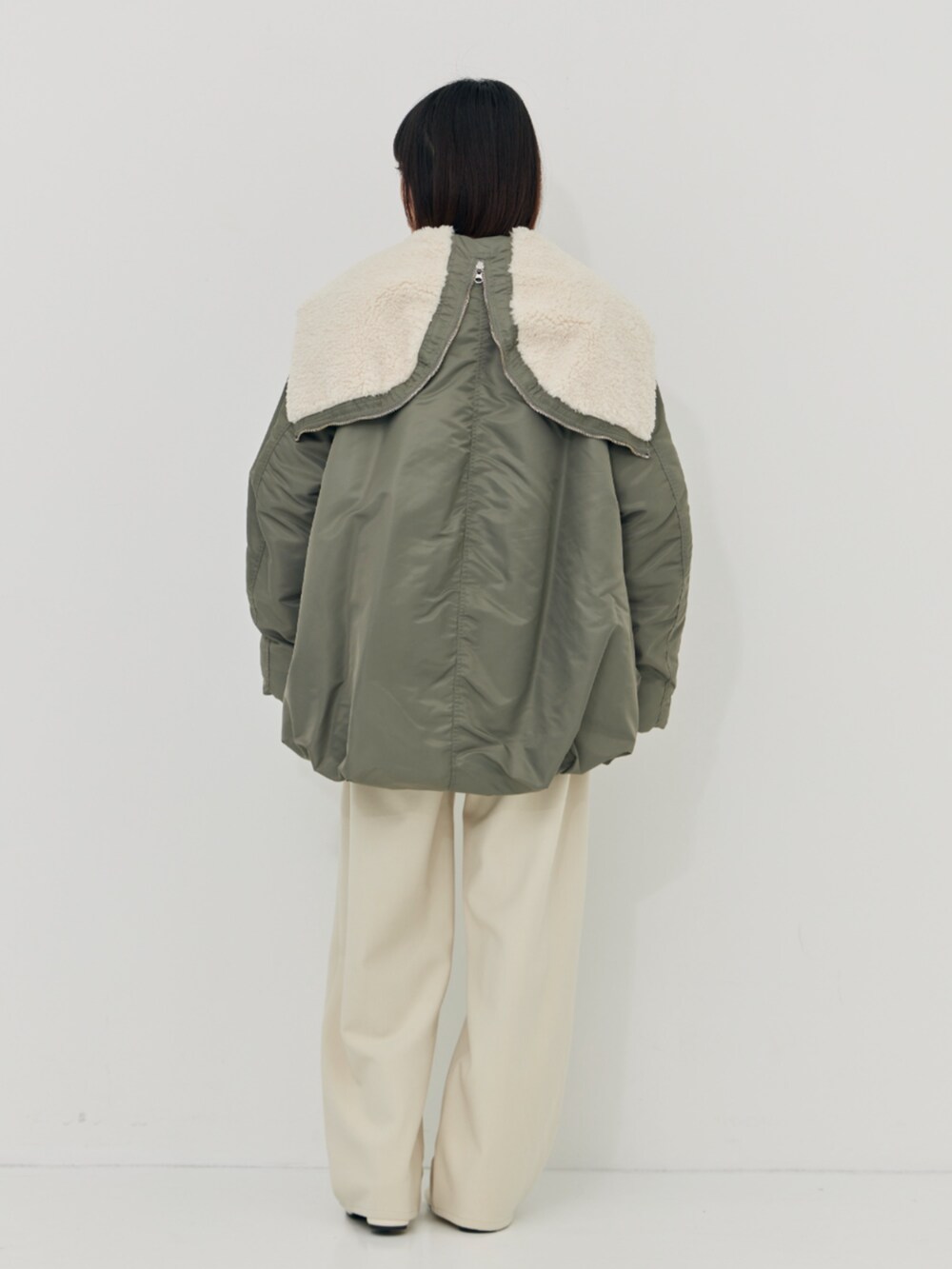 グリーン系のブルゾン、ホワイト系のその他パンツを着用したレディースの秋コーディネートの3枚目の写真