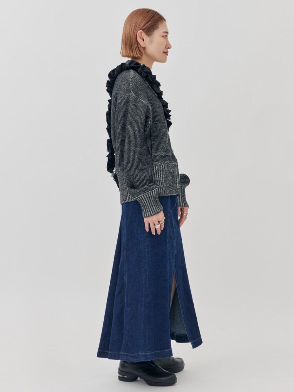 ブラック系のニット/セーター、ブラック系のショルダーバッグ、ブルー系のスカートを着用したレディースの秋コーディネートの5枚目の写真