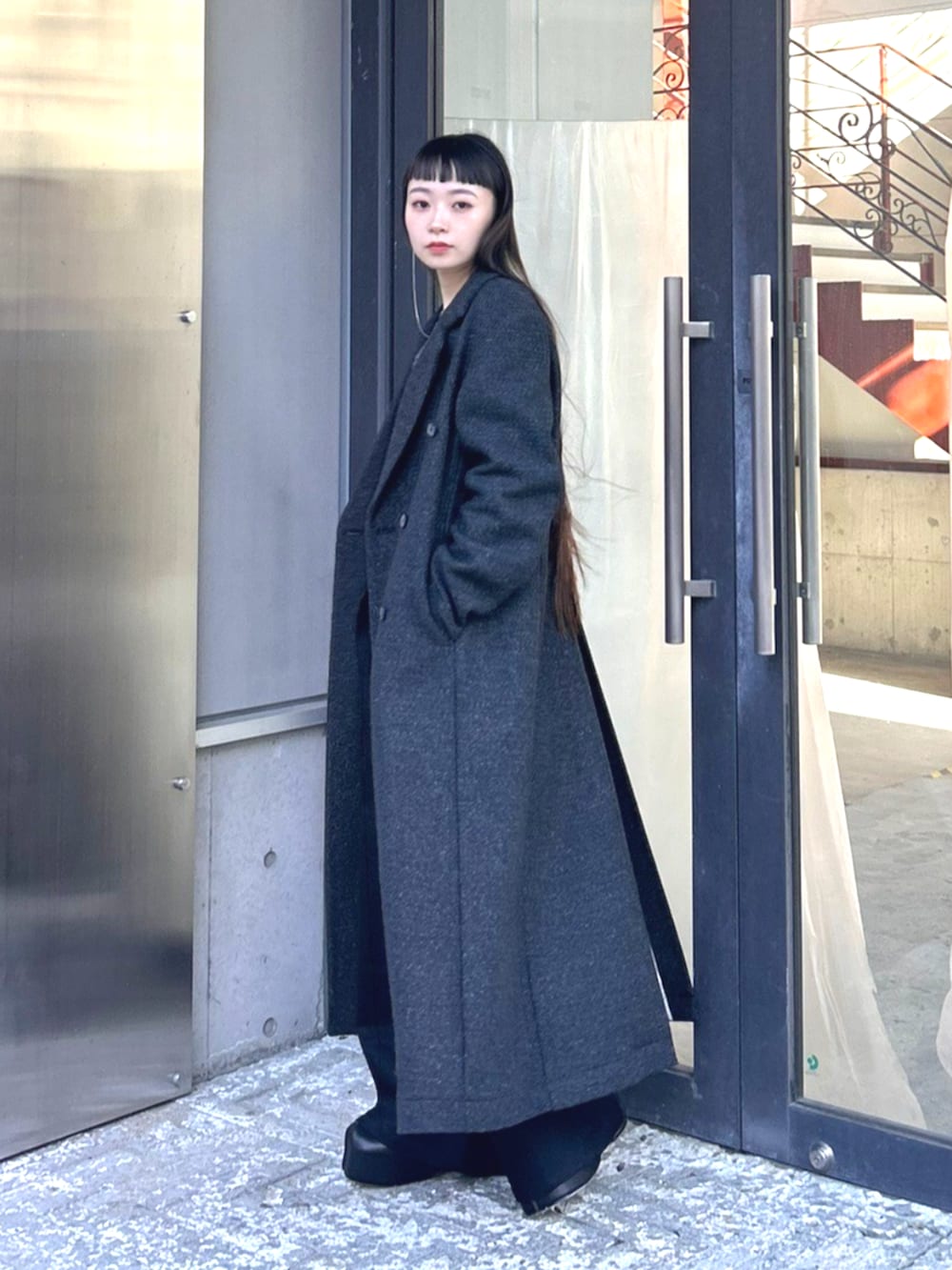 グレー系のチェスターコートを着用したレディースの秋コーディネートの2枚目の写真