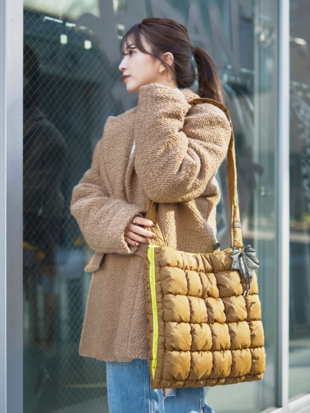 イエロー系のその他アウター、ブラウン系のショルダーバッグを着用したレディースの冬コーディネートの4枚目の写真