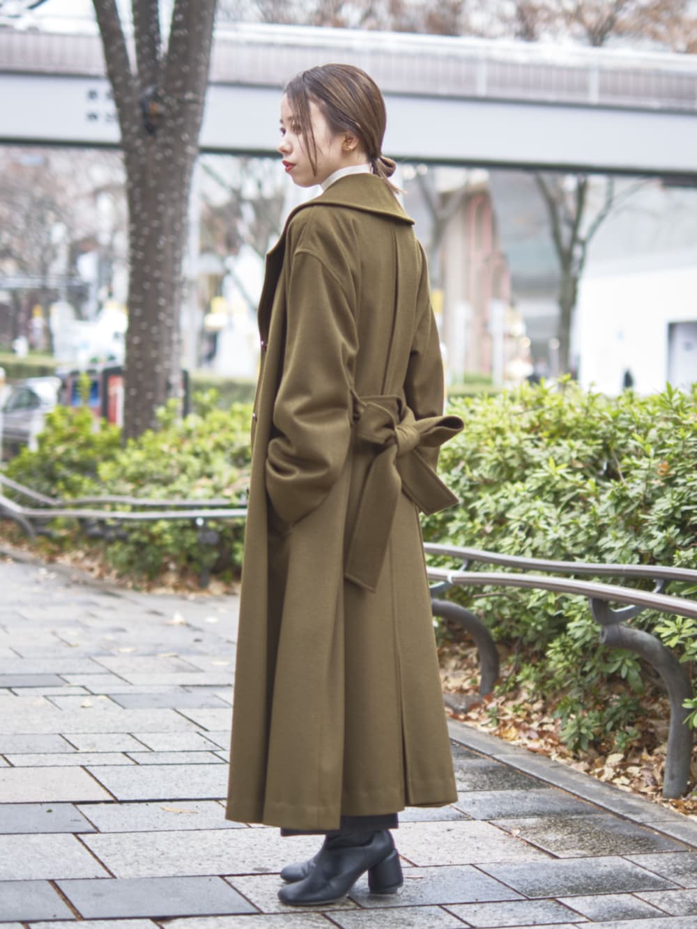 グリーン系のチェスターコートを着用したレディースの冬コーディネートの3枚目の写真