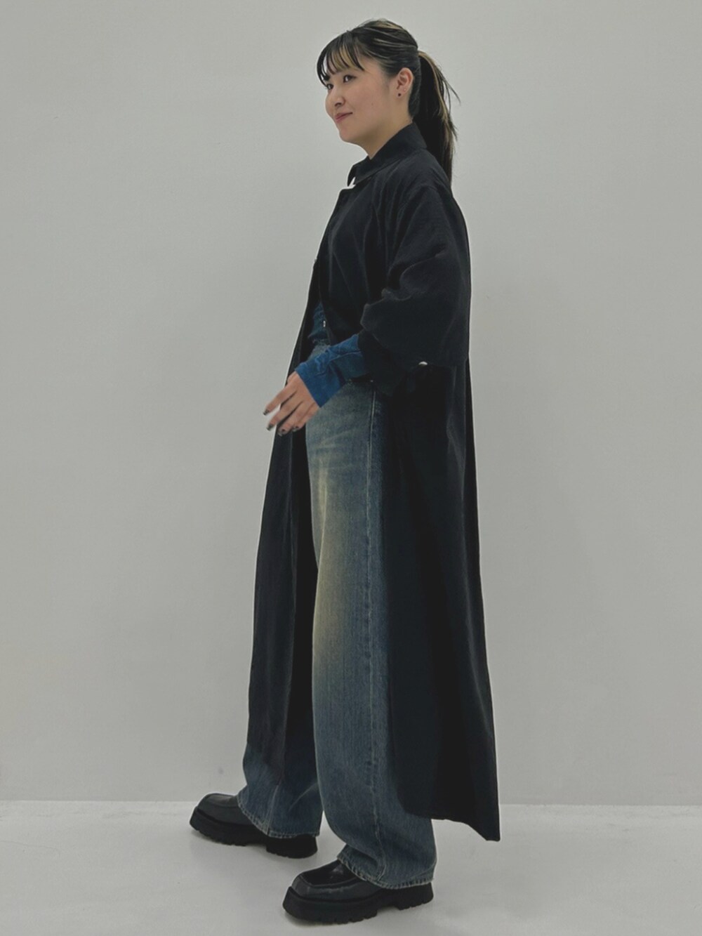 ブルー系のTシャツ/カットソー、ブラック系のステンカラーコート、ブルー系のデニムパンツを着用したレディースの秋コーディネートの2枚目の写真