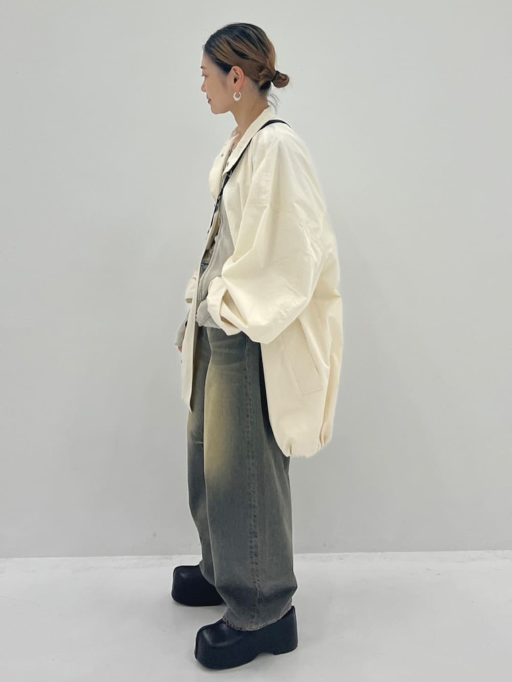 ブルー系のデニムパンツ、ブラック系のスリッポン、ホワイト系のブルゾンを着用したレディースの秋コーディネートの2枚目の写真