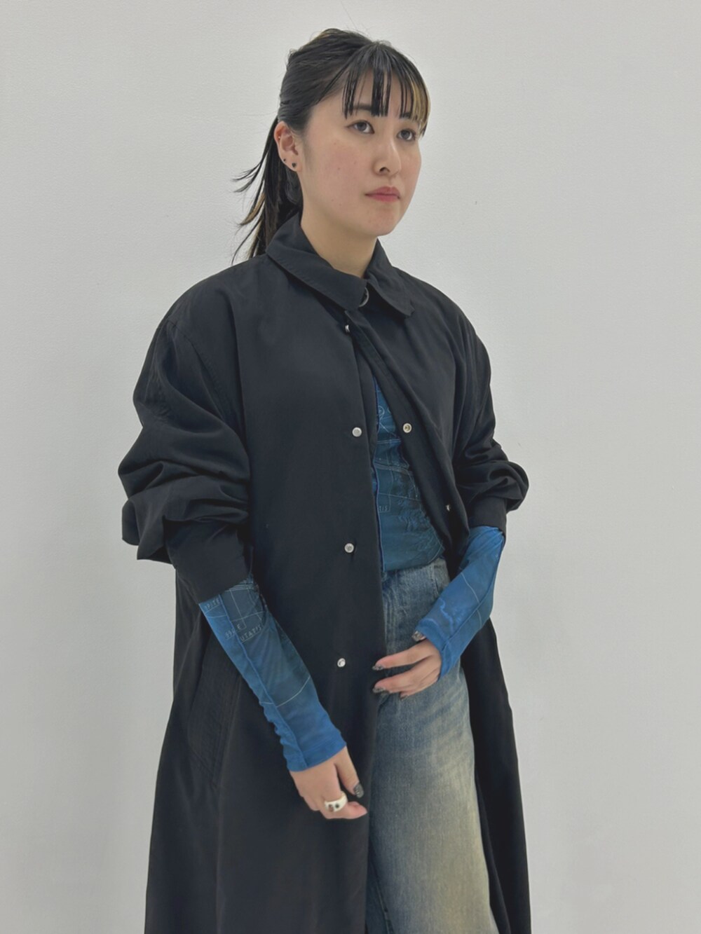 ブルー系のTシャツ/カットソー、ブラック系のステンカラーコート、ブルー系のデニムパンツを着用したレディースの秋コーディネートの3枚目の写真