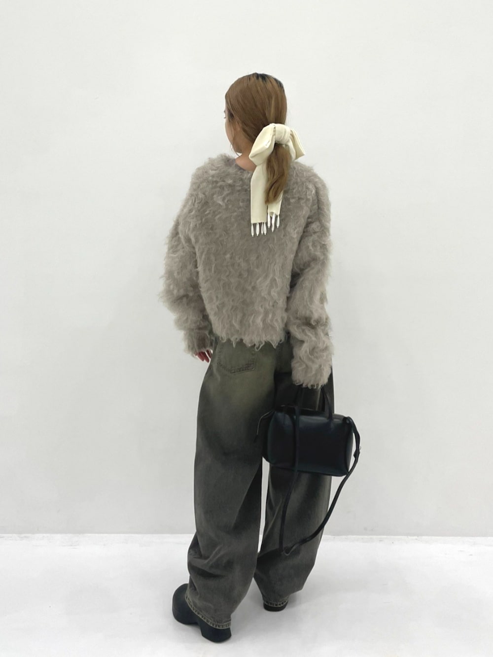 グレー系のタンクトップ、ブラック系のハンドバッグ、ベージュ系のカーディガン/ボレロを着用したレディースの秋コーディネートの2枚目の写真