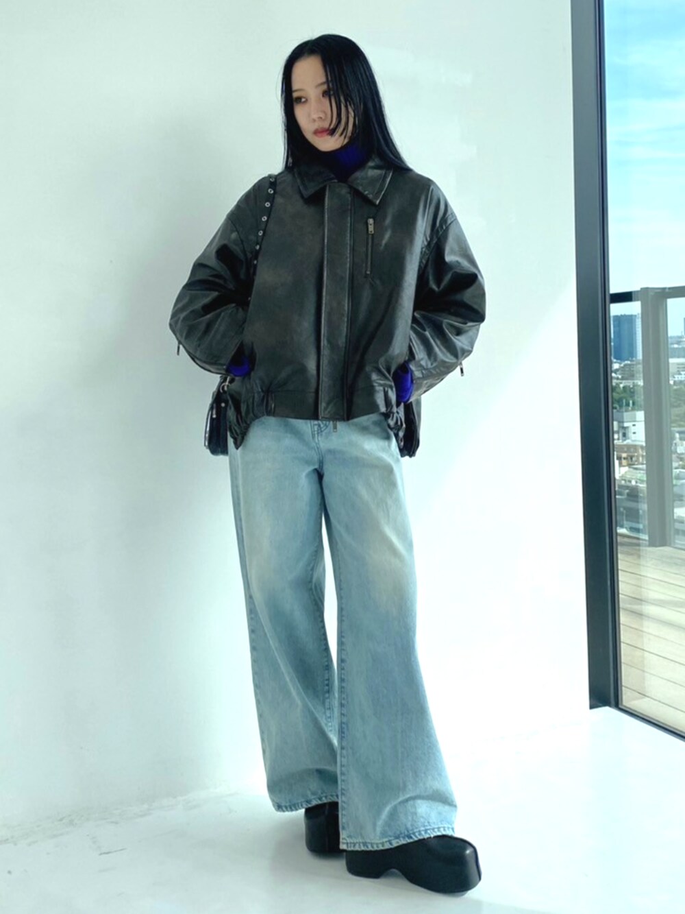 ブルー系のデニムパンツ、ブラウン系のブルゾン、ブルー系のニット/セーターを着用したレディースの秋コーディネートの2枚目の写真