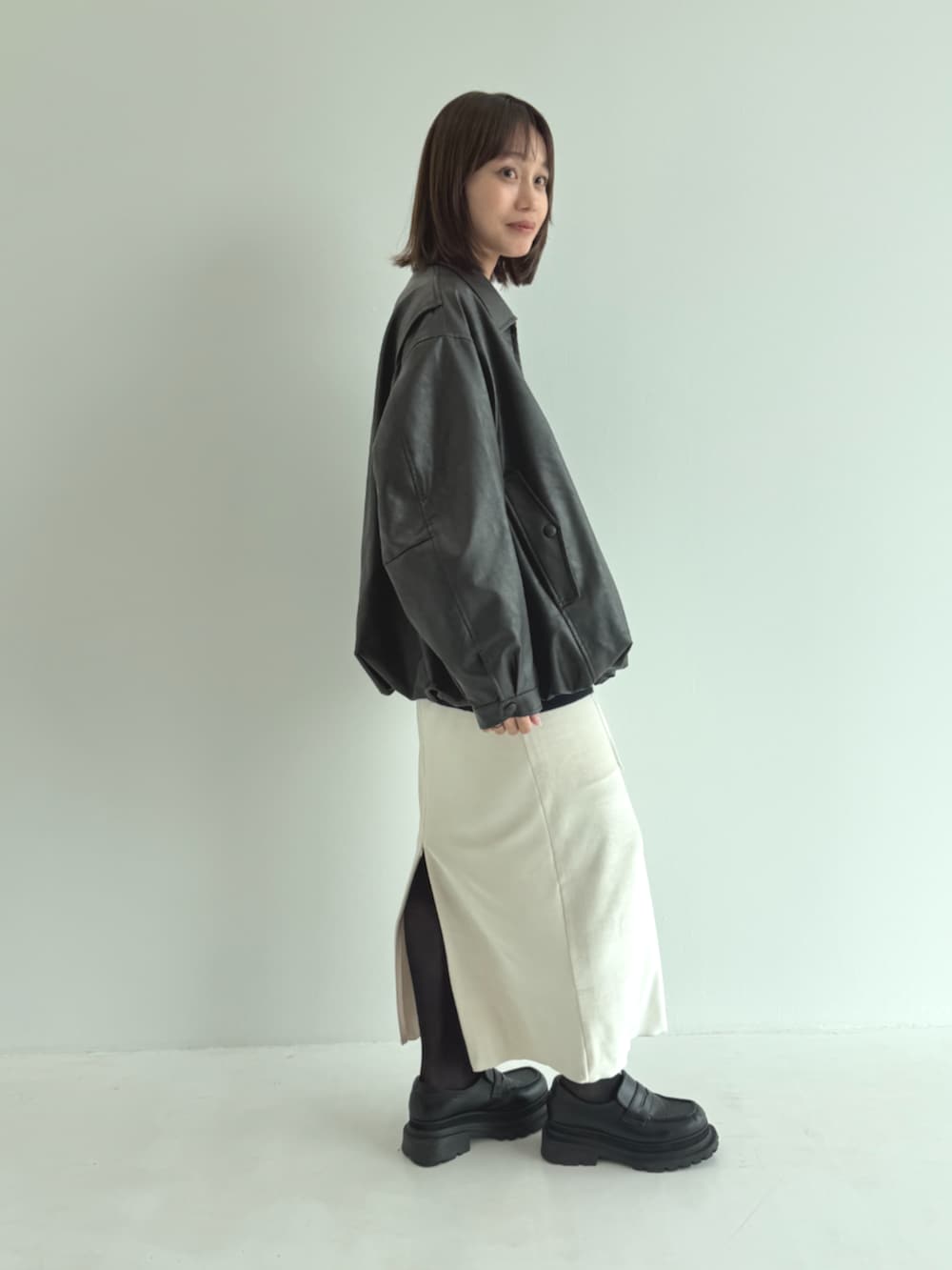 ブルー系のカーディガン/ボレロ、ブラック系のライダースジャケット、ベージュ系のスカートを着用したレディースの秋コーディネートの3枚目の写真