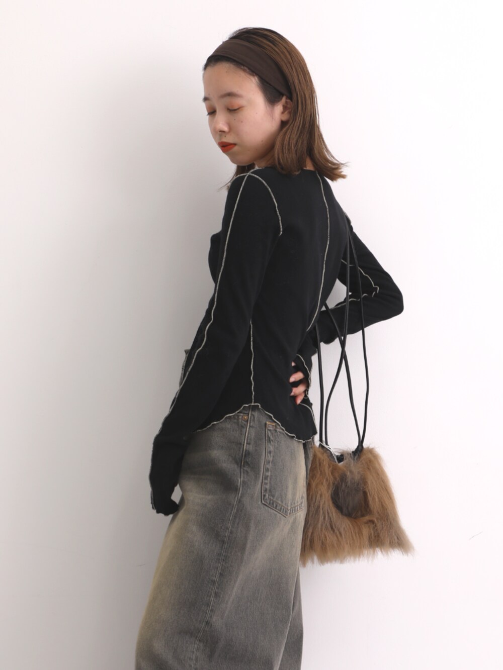 ブラック系のカーディガン/ボレロ、ブラック系のデニムパンツ、ブラウン系のハンドバッグを着用したレディースの秋コーディネートの3枚目の写真