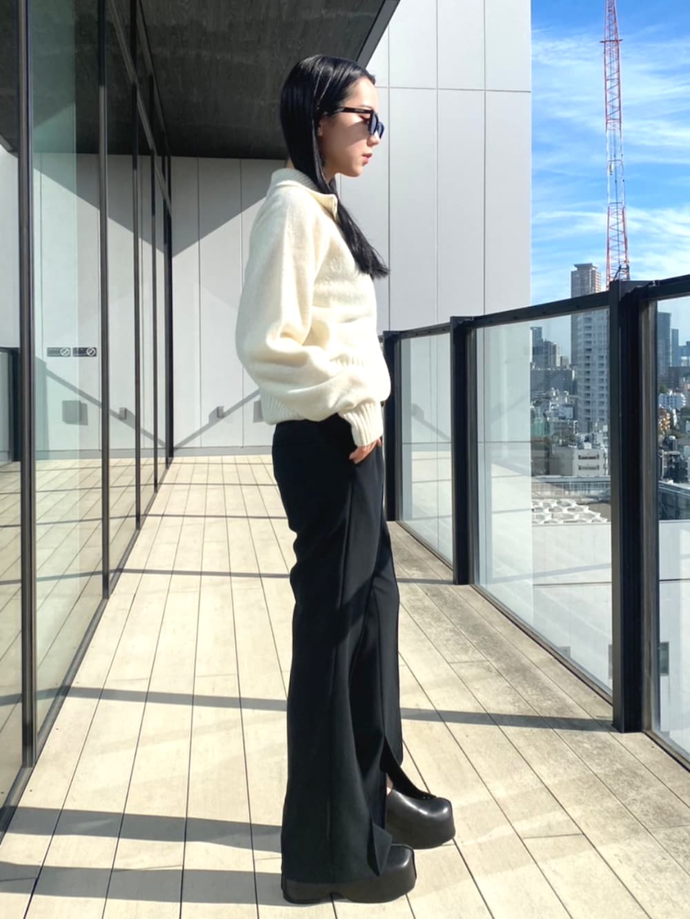 ブラック系のスラックス、ホワイト系のニット/セーターを着用したレディースの秋コーディネートの2枚目の写真