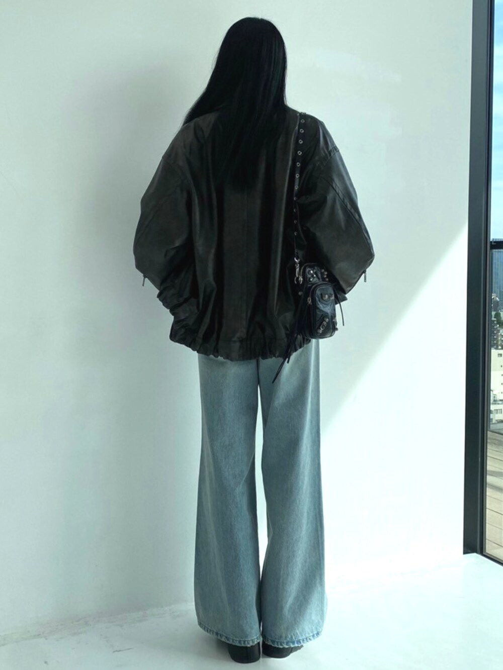 ブルー系のデニムパンツ、ブラウン系のブルゾン、ブルー系のニット/セーターを着用したレディースの秋コーディネートの3枚目の写真