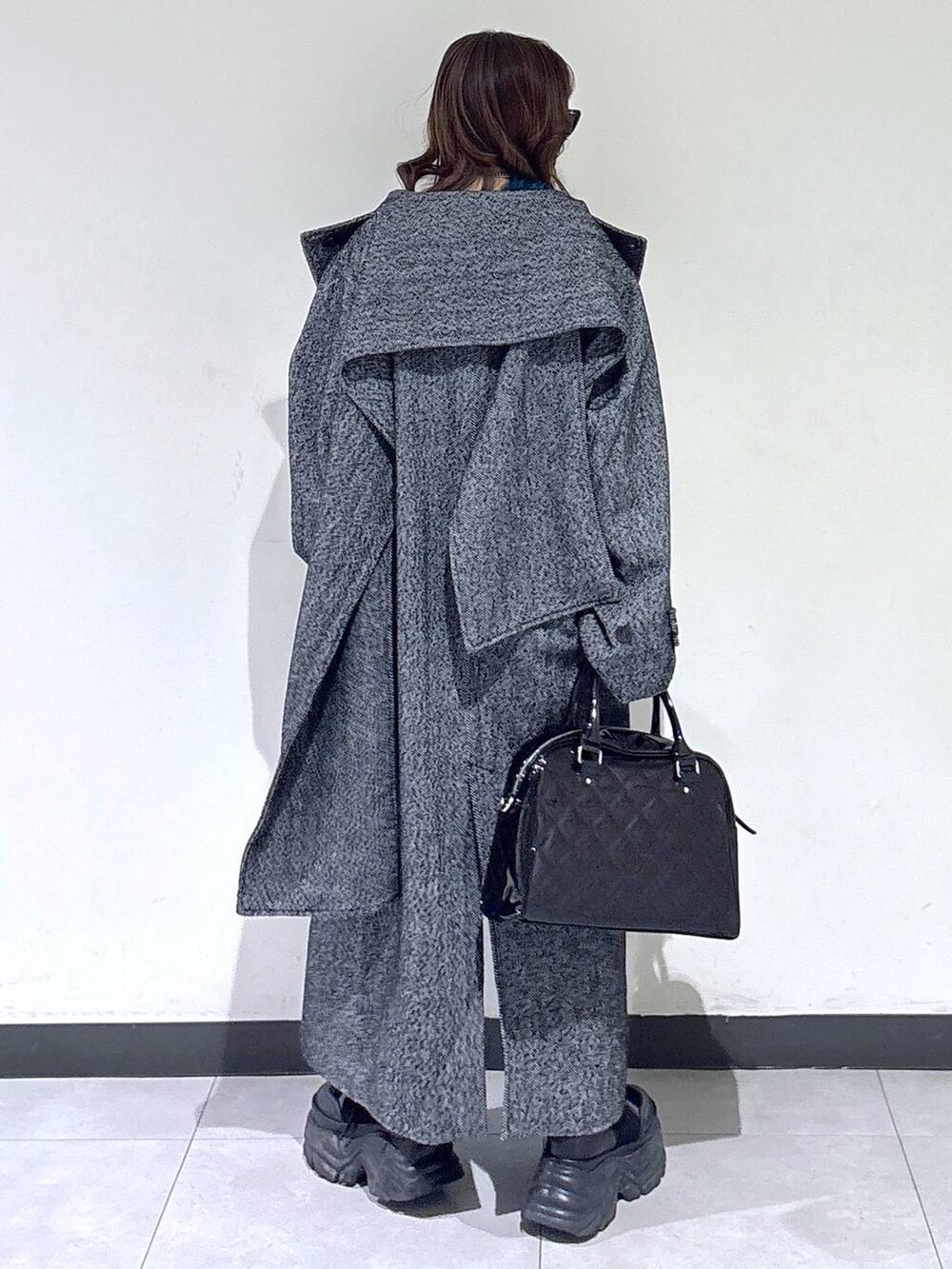 ブラック系のブーツ、ブラック系のチェスターコート、ブラウン系のスカートを着用したレディースの冬コーディネートの4枚目の写真