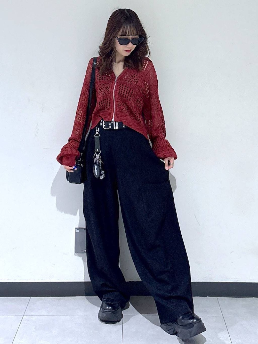 ブラック系のブーツ、ブラック系のショルダーバッグ、レッド系のパーカーを着用したレディースの春コーディネートの3枚目の写真