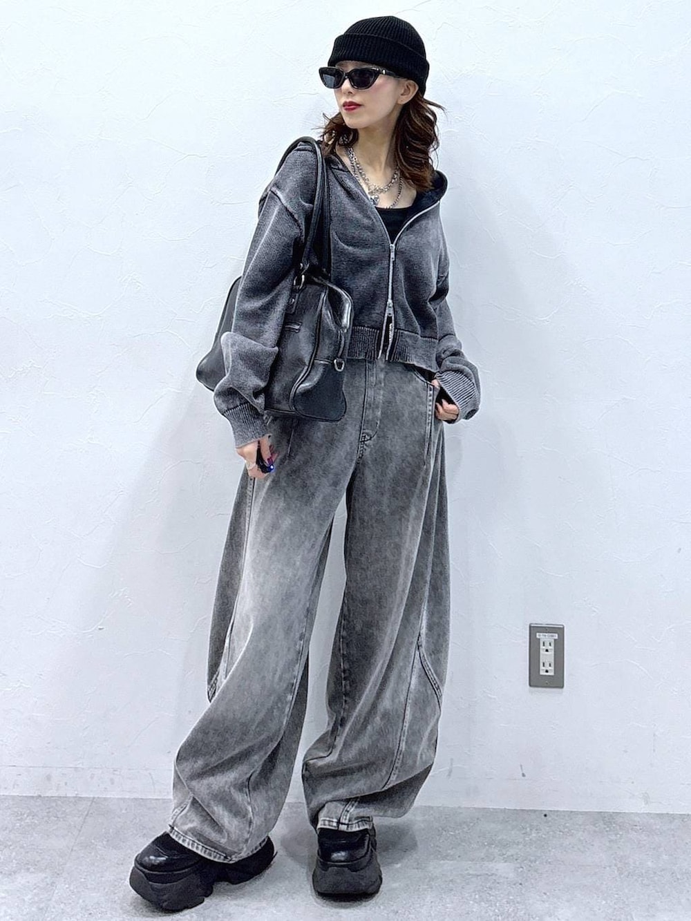 ブラック系のブーツ、ブラック系のボストンバッグ、グレー系のパーカーを着用したレディースの冬コーディネートの2枚目の写真