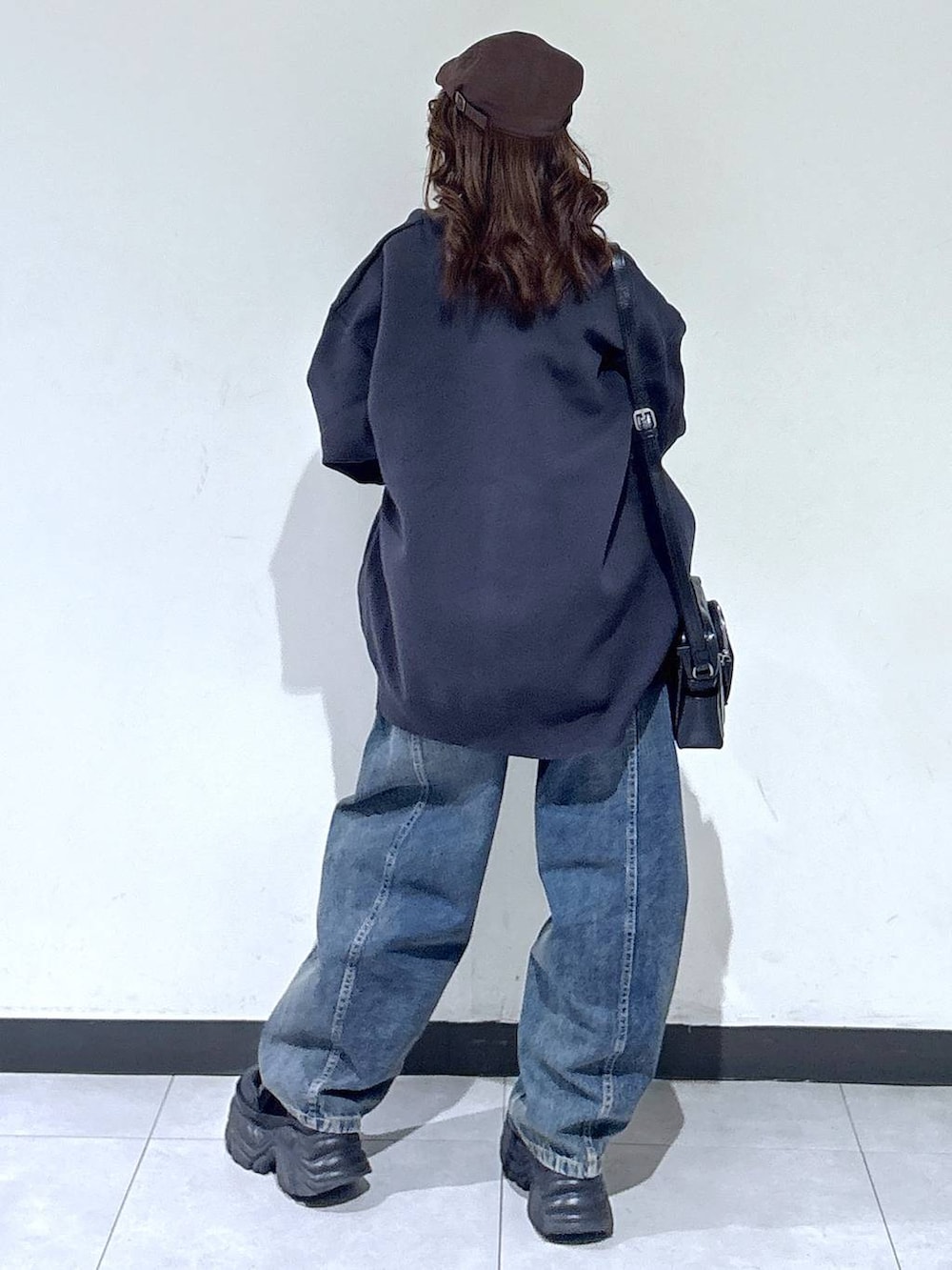 ブラック系のブーツ、ブルー系のデニムパンツ、ブラック系のショルダーバッグを着用したレディースの春コーディネートの6枚目の写真