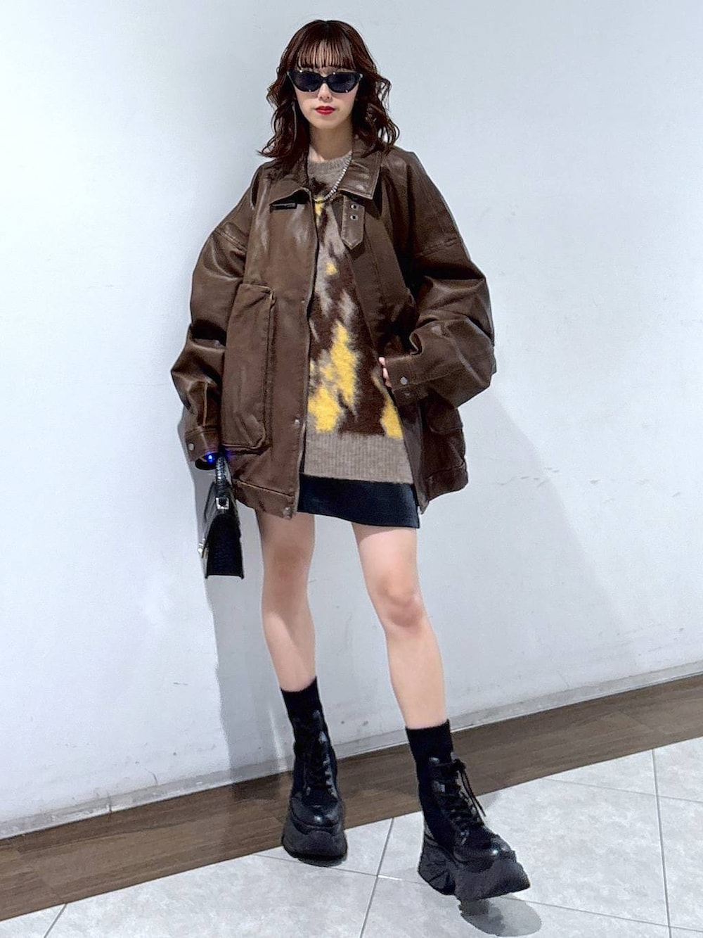 ブラック系のブーツ、ブラック系のハンドバッグ、ブラウン系のブルゾンを着用したレディースの秋コーディネートの3枚目の写真