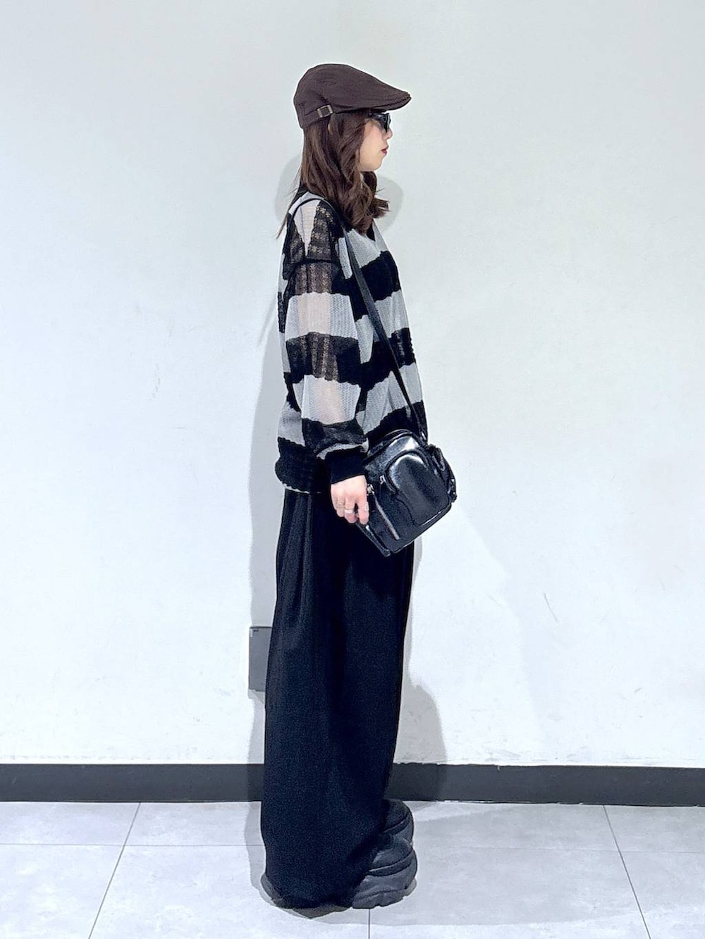 ブラック系のブーツ、ブラック系のスラックス、ブラック系のショルダーバッグを着用したレディースの春コーディネートの3枚目の写真