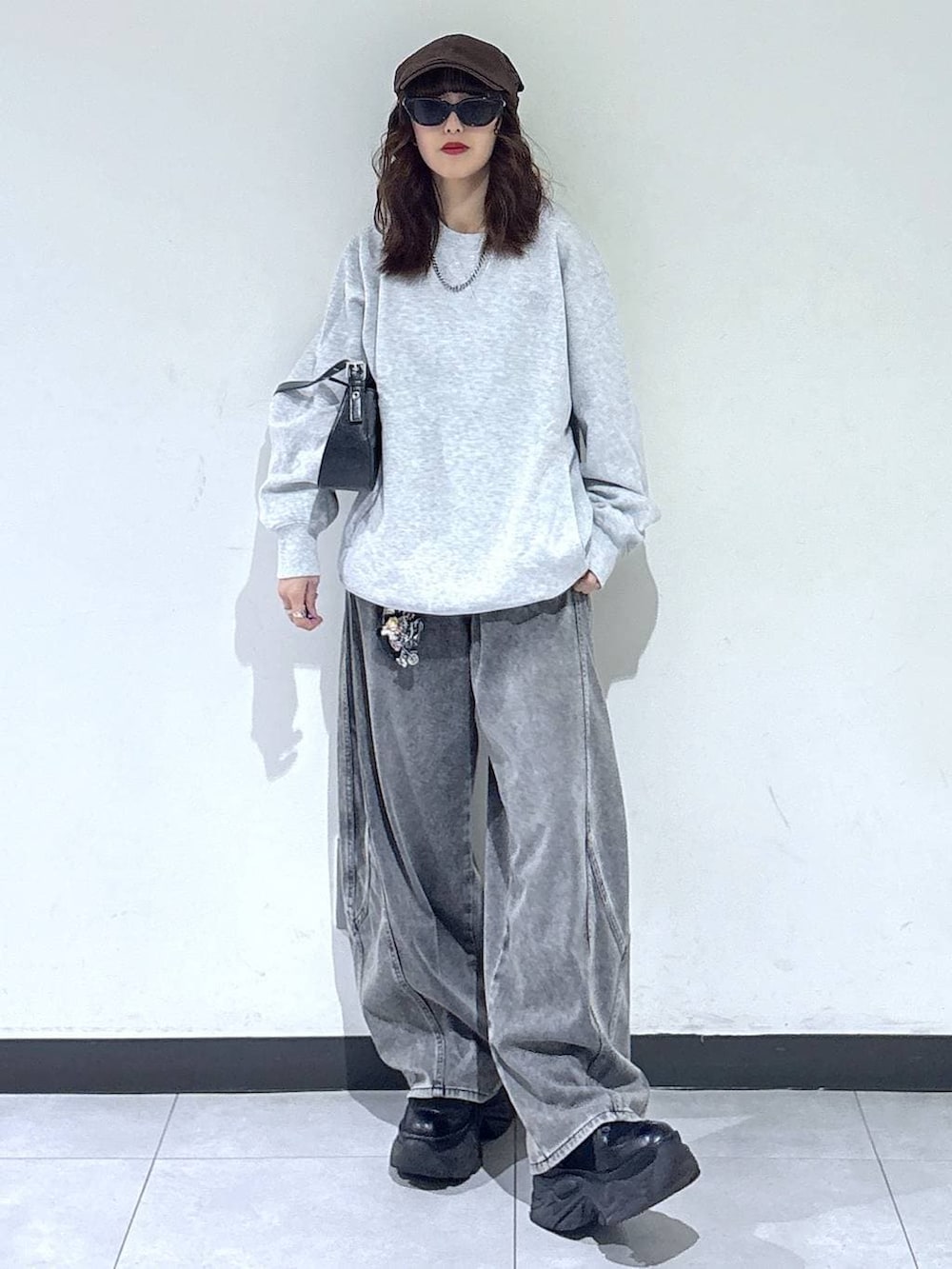 ブラック系のブーツ、グレー系のスウェット、ブラック系のハンドバッグを着用したレディースの春コーディネートの2枚目の写真