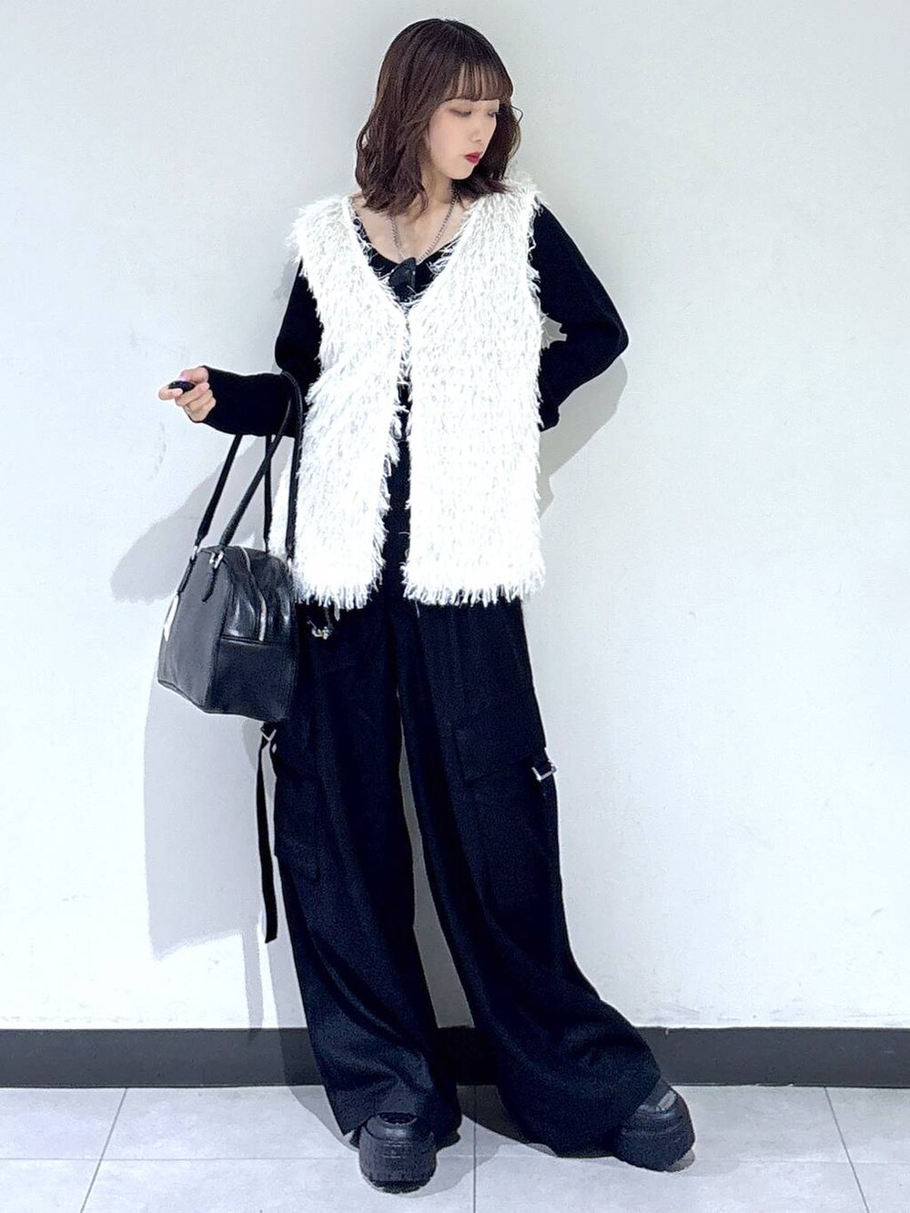 ホワイト系のベスト、ブラック系のTシャツ/カットソー、ブラック系のボストンバッグを着用したレディースの秋コーディネートの6枚目の写真