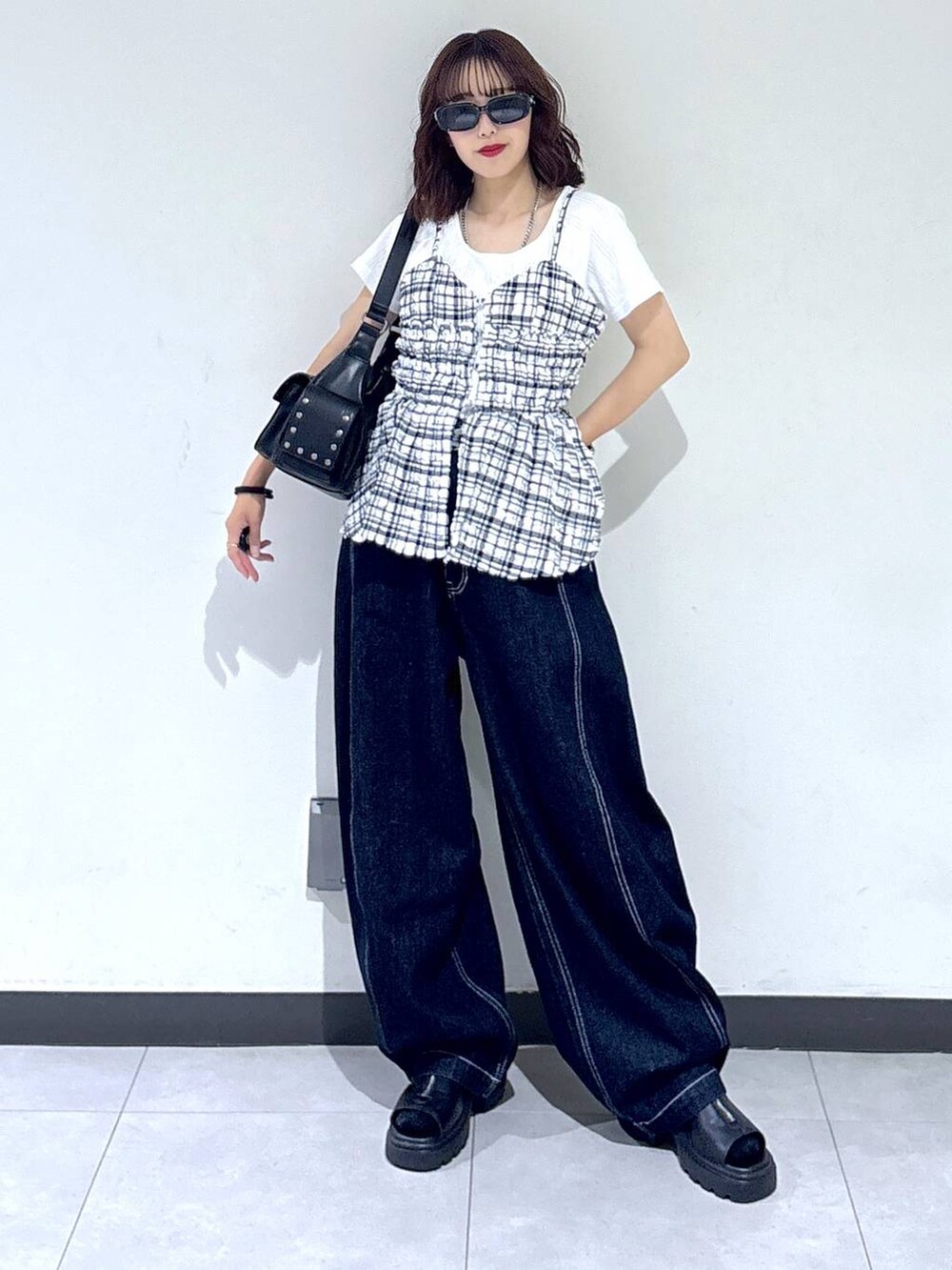 ブラック系のサンダル、ブルー系のデニムパンツ、ブラック系のショルダーバッグを着用したレディースの夏コーディネートの5枚目の写真