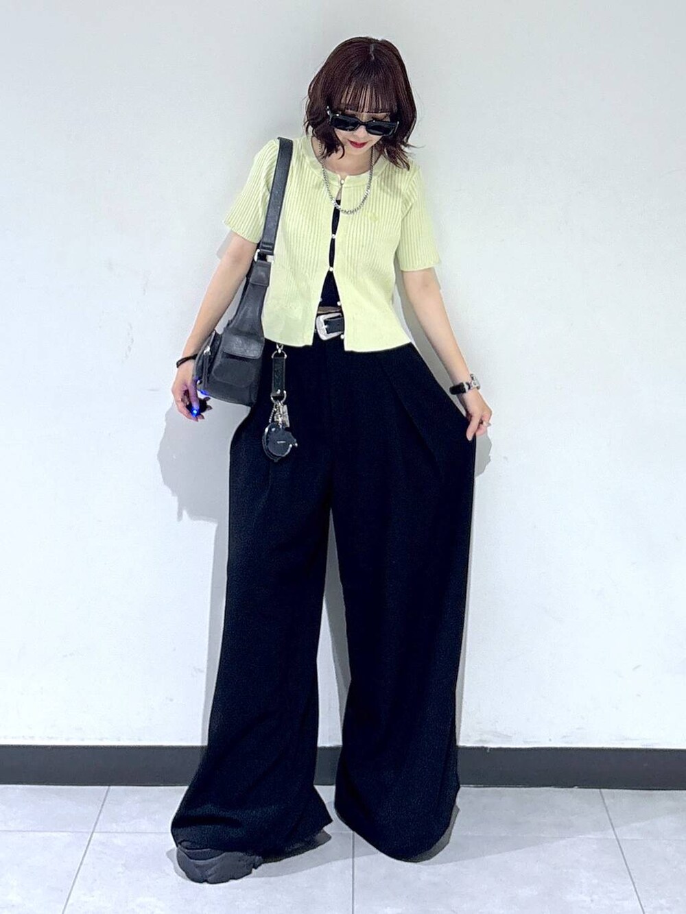 ブラック系のブーツ、ブラック系のスラックス、ブラック系のショルダーバッグを着用したレディースの夏コーディネートの2枚目の写真