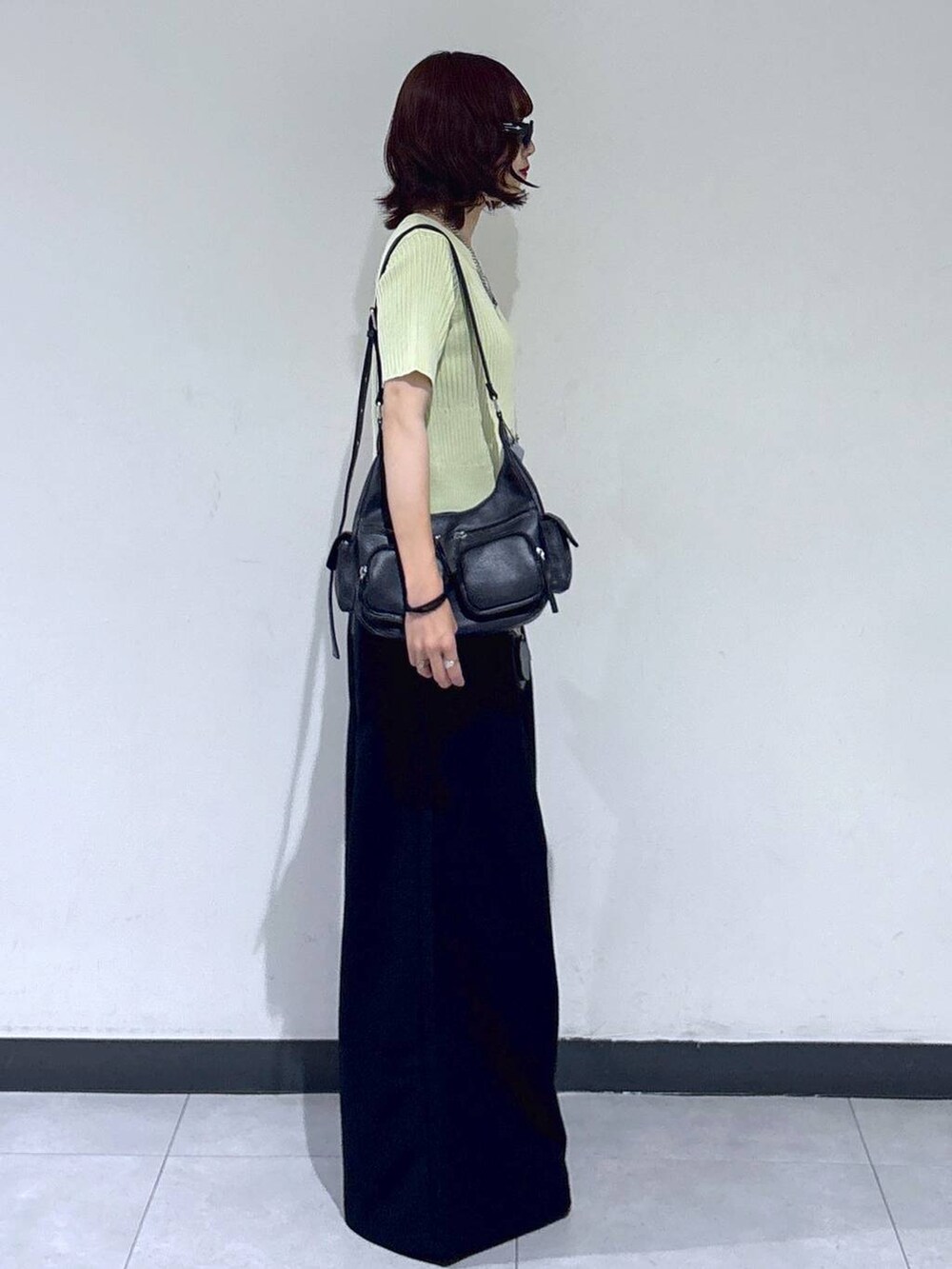 ブラック系のブーツ、ブラック系のスラックス、ブラック系のショルダーバッグを着用したレディースの夏コーディネートの5枚目の写真