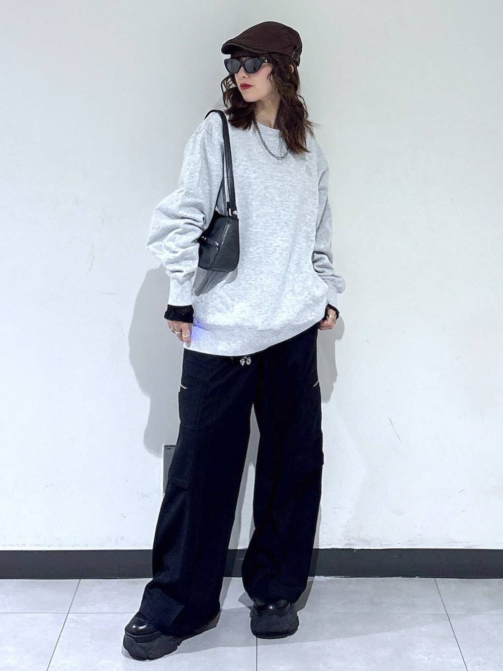 ブラック系のブーツ、グレー系のスウェット、ブラック系のスラックスを着用したレディースの春コーディネートの2枚目の写真