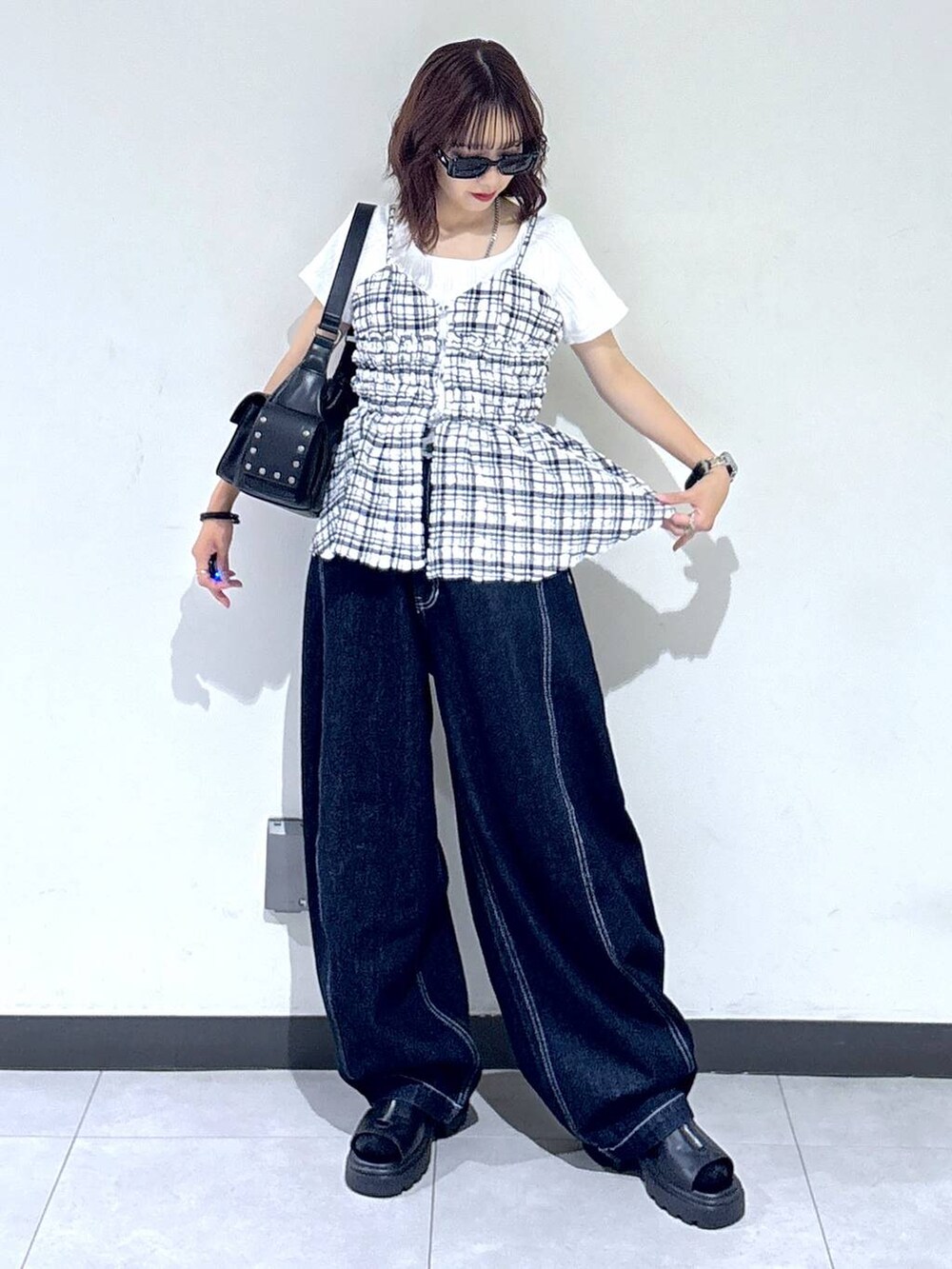 ブラック系のサンダル、ブルー系のデニムパンツ、ブラック系のショルダーバッグを着用したレディースの夏コーディネートの4枚目の写真