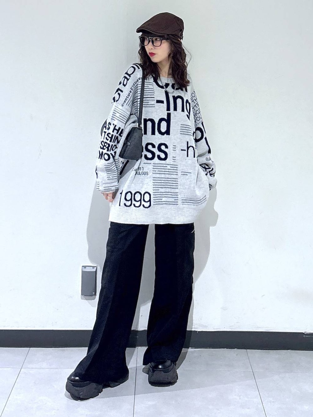 ブラック系のブーツ、ブラック系のハンドバッグ、グレー系のニット/セーターを着用したレディースの春コーディネートの3枚目の写真