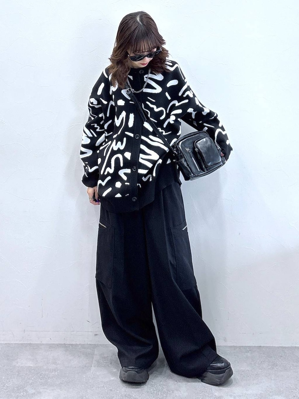 ブラック系のブーツ、ホワイト系のカーディガン/ボレロ、ブラック系のスラックスを着用したレディースの冬コーディネートの2枚目の写真