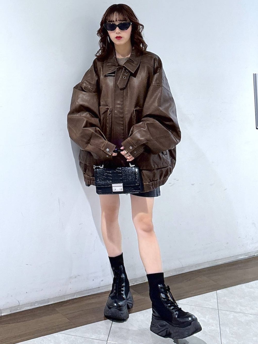 ブラック系のブーツ、ブラック系のハンドバッグ、ブラウン系のブルゾンを着用したレディースの秋コーディネートの4枚目の写真