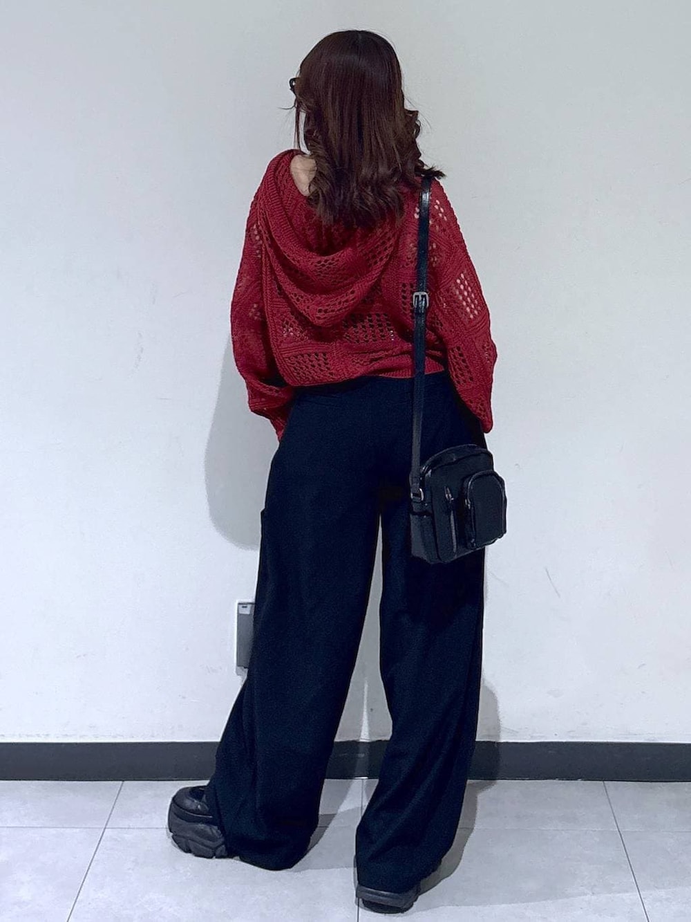 ブラック系のブーツ、ブラック系のショルダーバッグ、レッド系のパーカーを着用したレディースの春コーディネートの5枚目の写真