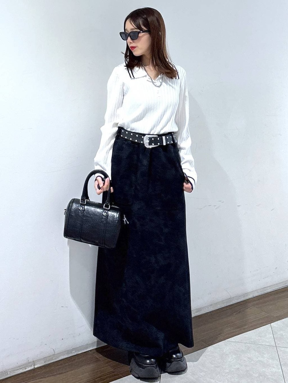 ブラック系のブーツ、ブラック系のスカート、ブラック系のボストンバッグを着用したレディースの春コーディネートの4枚目の写真