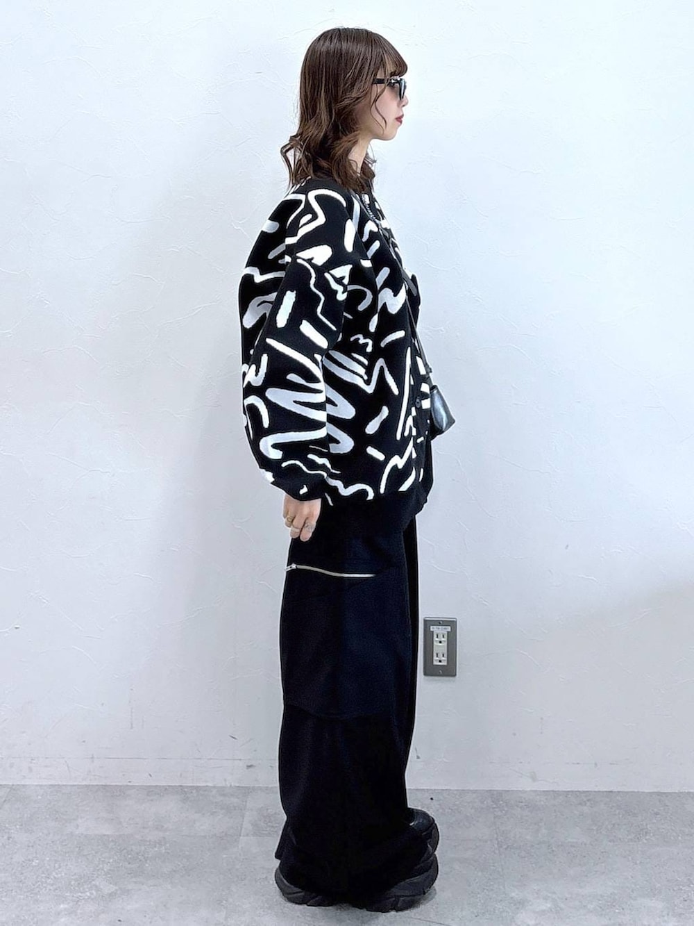 ブラック系のブーツ、ホワイト系のカーディガン/ボレロ、ブラック系のスラックスを着用したレディースの冬コーディネートの3枚目の写真