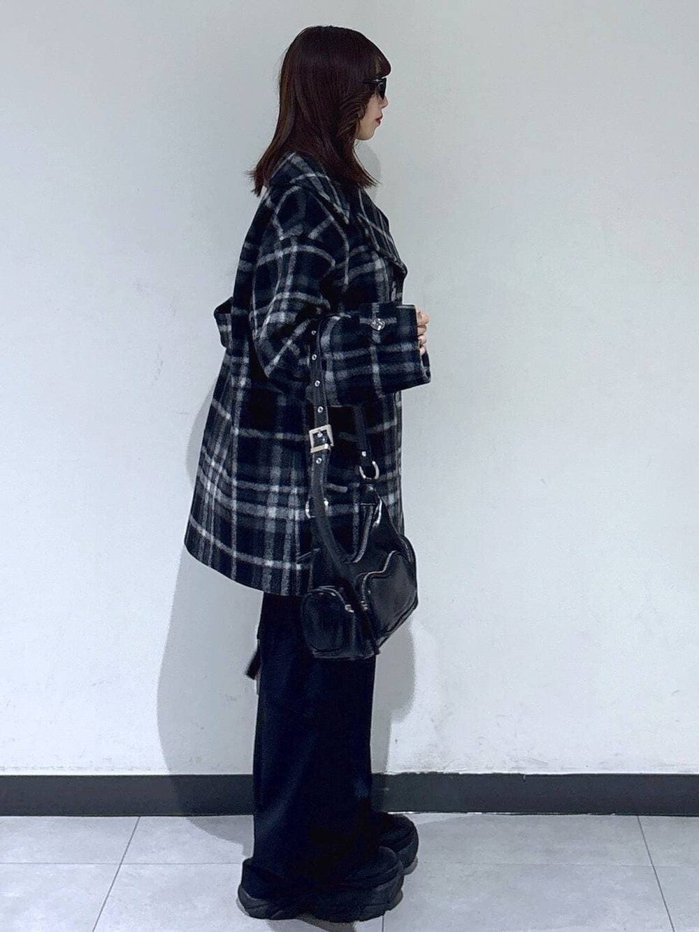 ブラック系のブーツ、ブラック系のチェスターコート、ブラック系のスラックスを着用したレディースの冬コーディネートの3枚目の写真