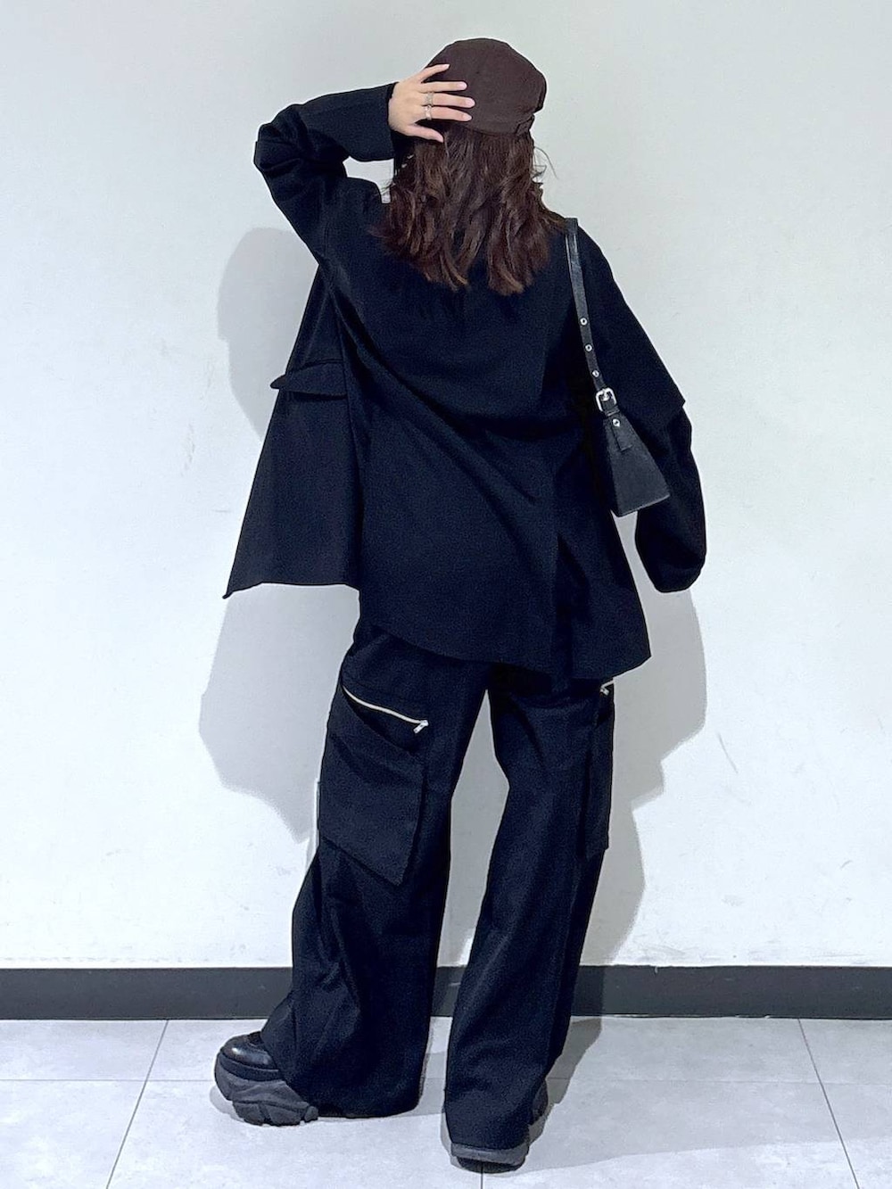 ブラック系のブーツ、ブラック系のハンドバッグ、ブラック系のスラックスを着用したレディースの春コーディネートの5枚目の写真