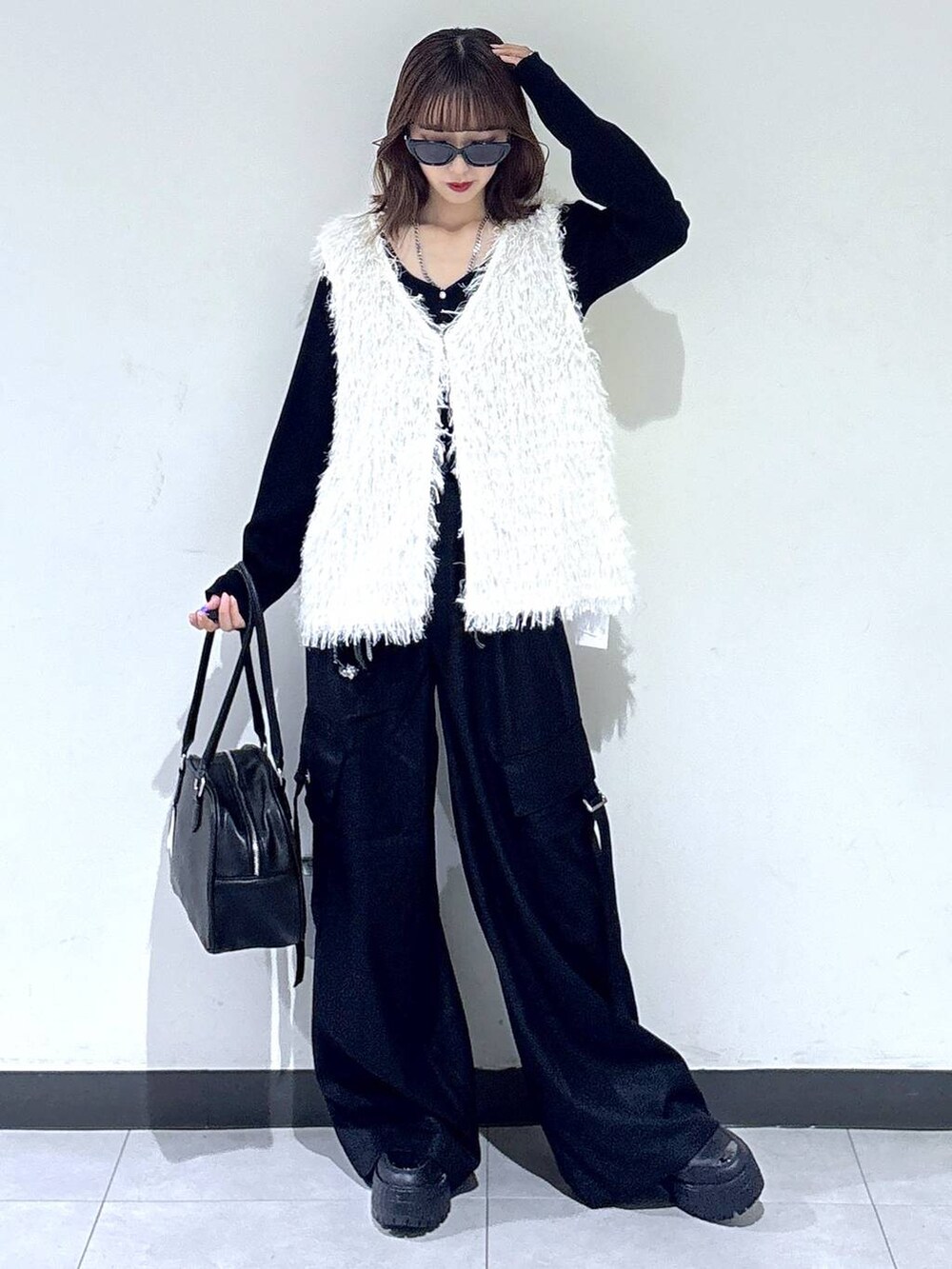 ホワイト系のベスト、ブラック系のTシャツ/カットソー、ブラック系のボストンバッグを着用したレディースの秋コーディネートの5枚目の写真