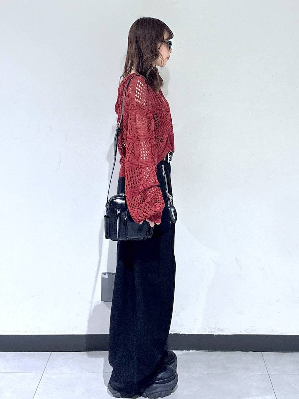 ブラック系のブーツ、ブラック系のショルダーバッグ、レッド系のパーカーを着用したレディースの春コーディネートの4枚目の写真