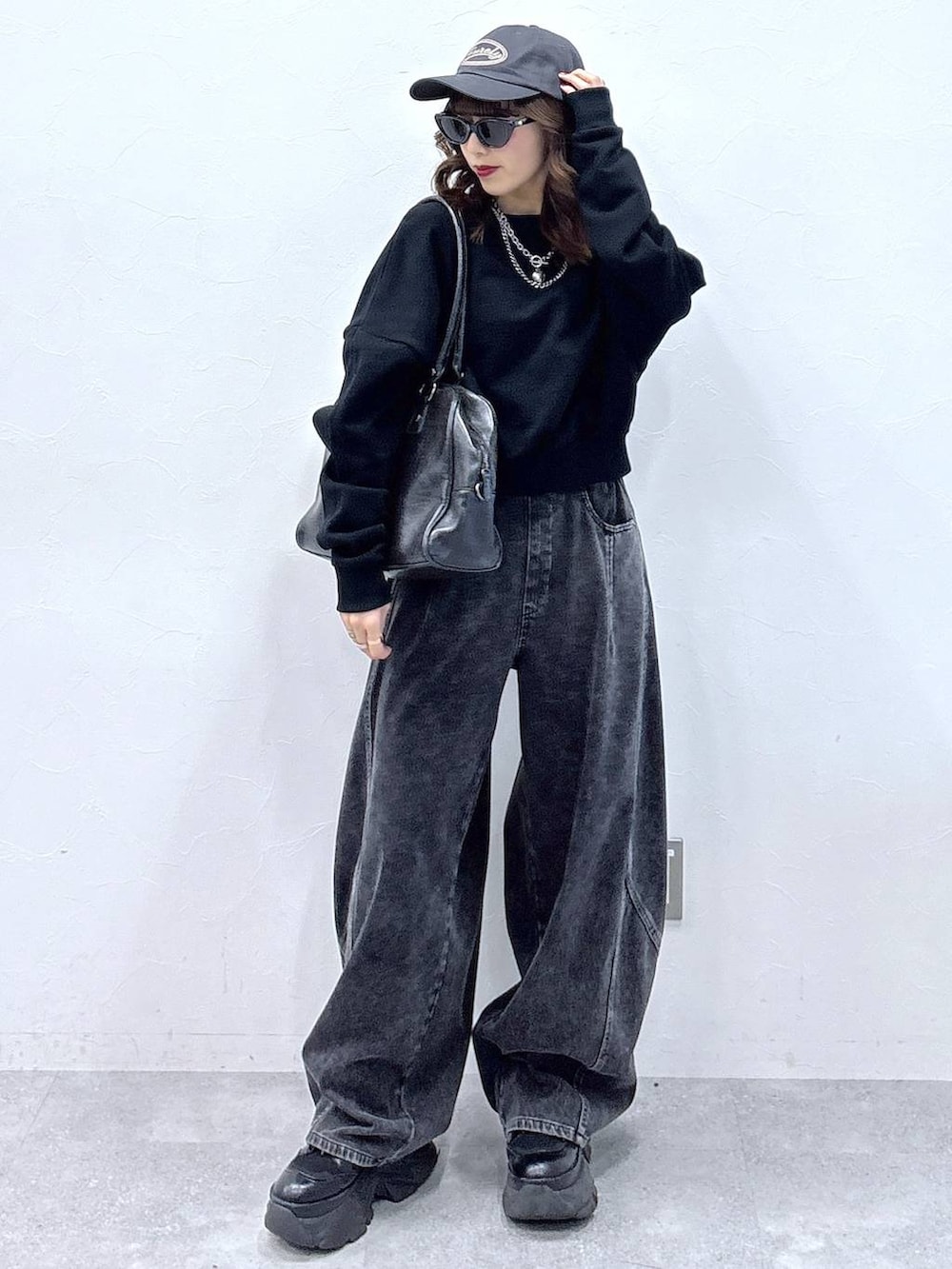 ブラック系のブーツ、ブラック系のボストンバッグ、ブラック系のデニムパンツを着用したレディースの冬コーディネートの2枚目の写真