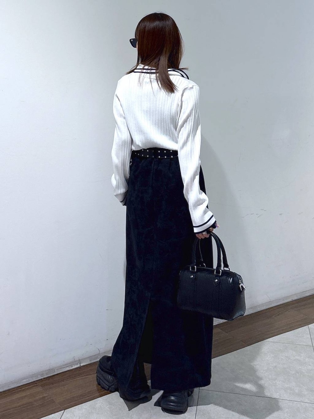 ブラック系のブーツ、ブラック系のスカート、ブラック系のボストンバッグを着用したレディースの春コーディネートの5枚目の写真