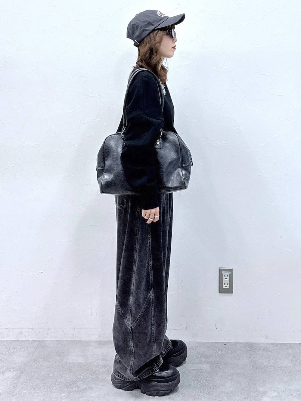 ブラック系のブーツ、ブラック系のボストンバッグ、ブラック系のデニムパンツを着用したレディースの冬コーディネートの5枚目の写真