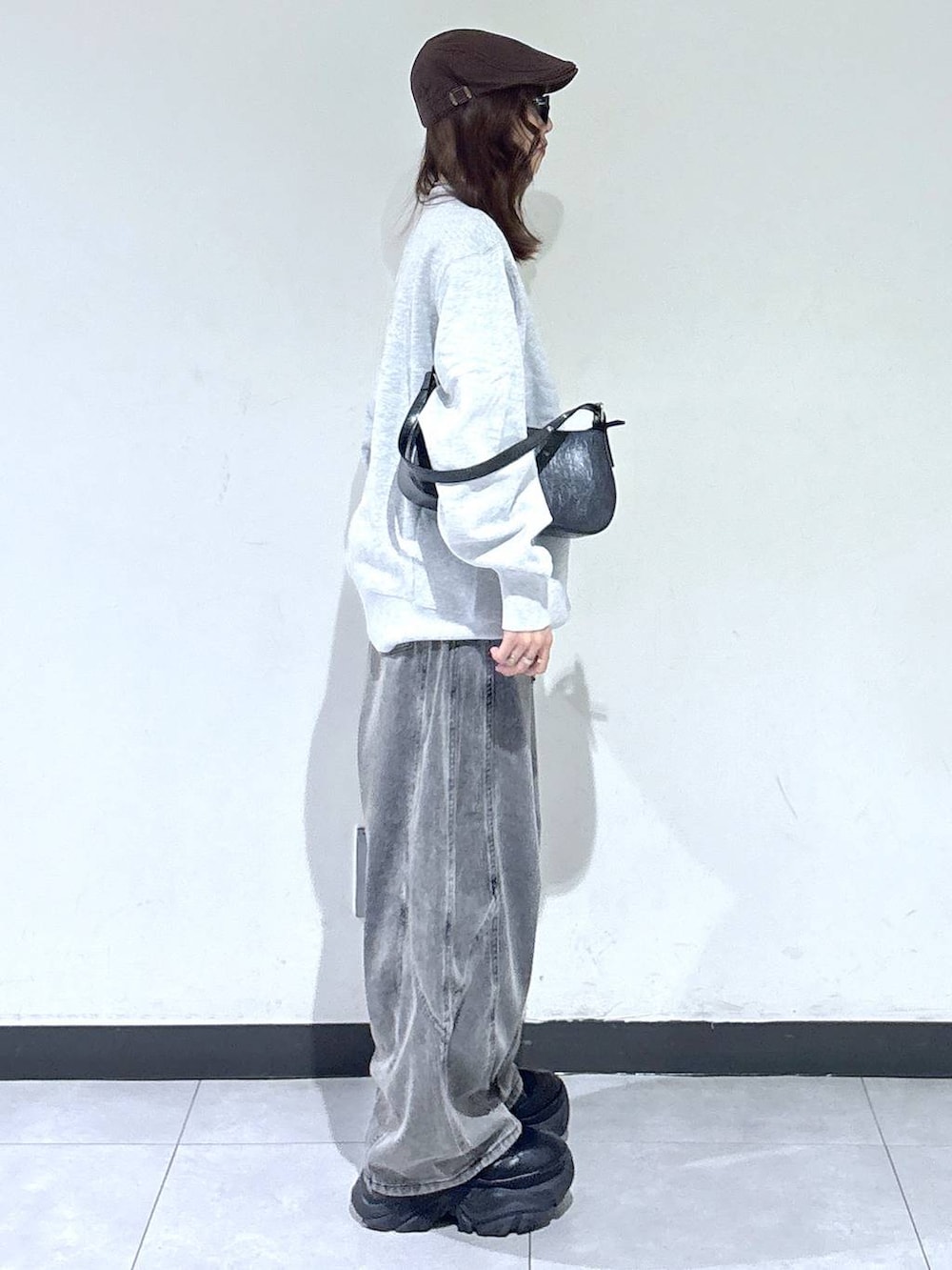 ブラック系のブーツ、グレー系のスウェット、ブラック系のハンドバッグを着用したレディースの春コーディネートの3枚目の写真