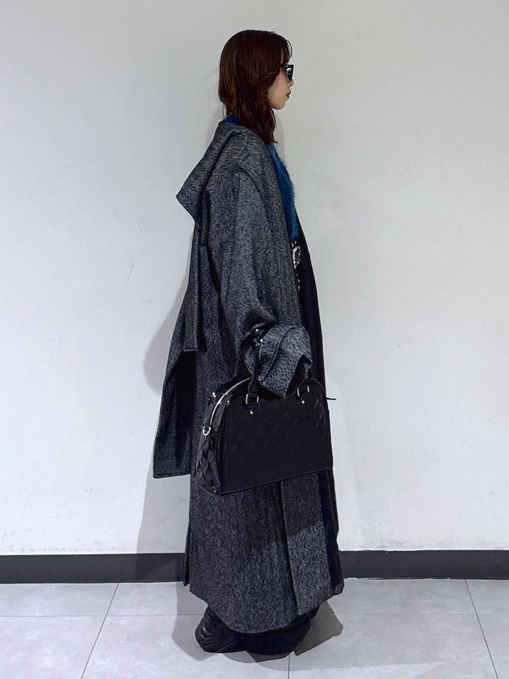 ブラック系のブーツ、ブラック系のチェスターコート、ブラウン系のスカートを着用したレディースの冬コーディネートの2枚目の写真