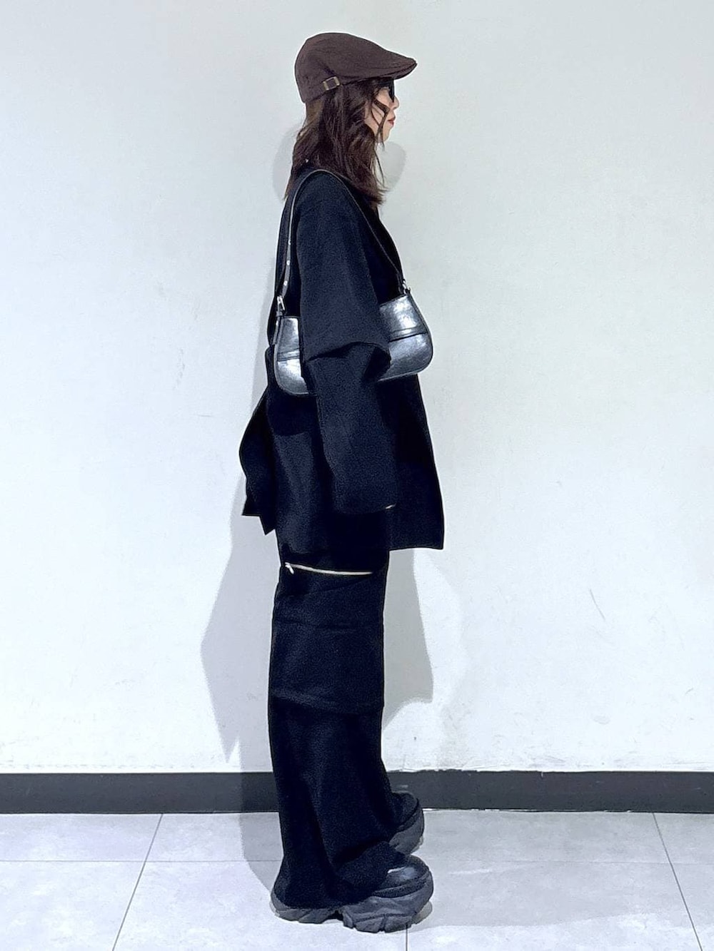 ブラック系のブーツ、ブラック系のハンドバッグ、ブラック系のスラックスを着用したレディースの春コーディネートの3枚目の写真