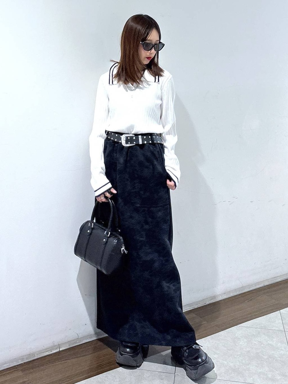 ブラック系のブーツ、ブラック系のスカート、ブラック系のボストンバッグを着用したレディースの春コーディネートの2枚目の写真