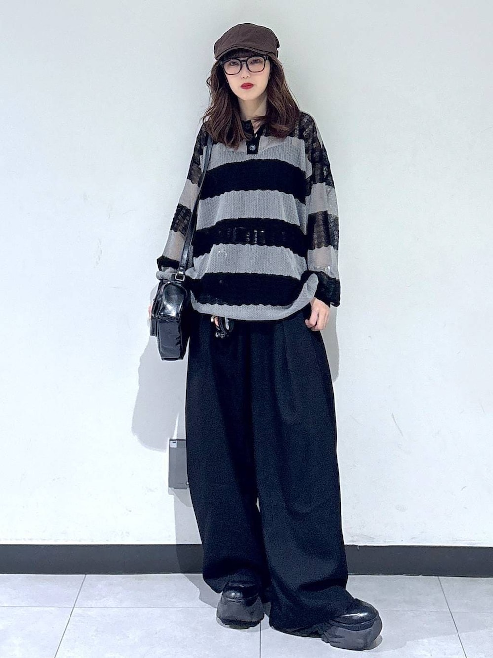 ブラック系のブーツ、ブラック系のスラックス、ブラック系のショルダーバッグを着用したレディースの春コーディネートの4枚目の写真